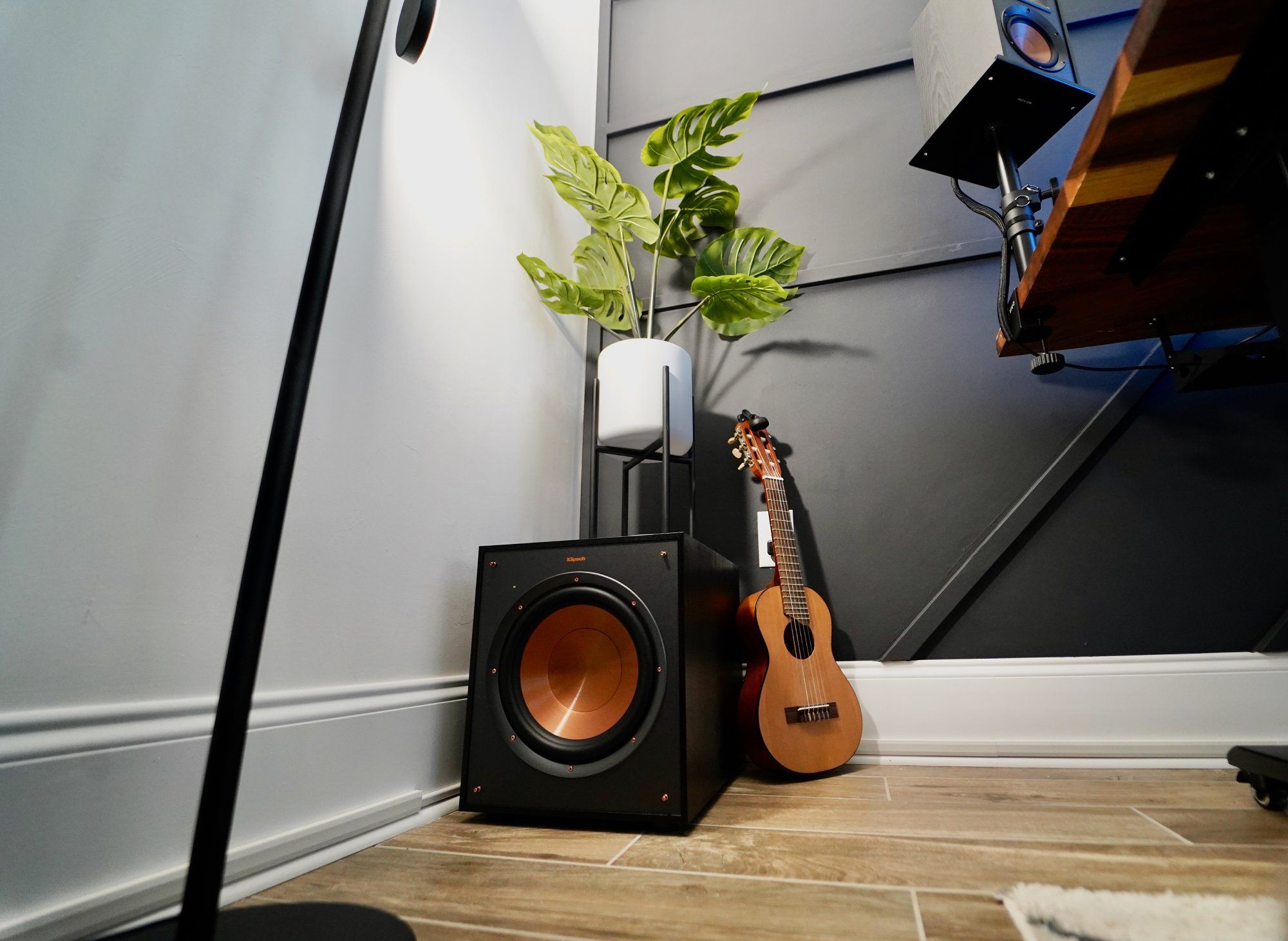 The guitar, a Klipsch subwoofer, and a potted indoor plant in the corner of a home office space