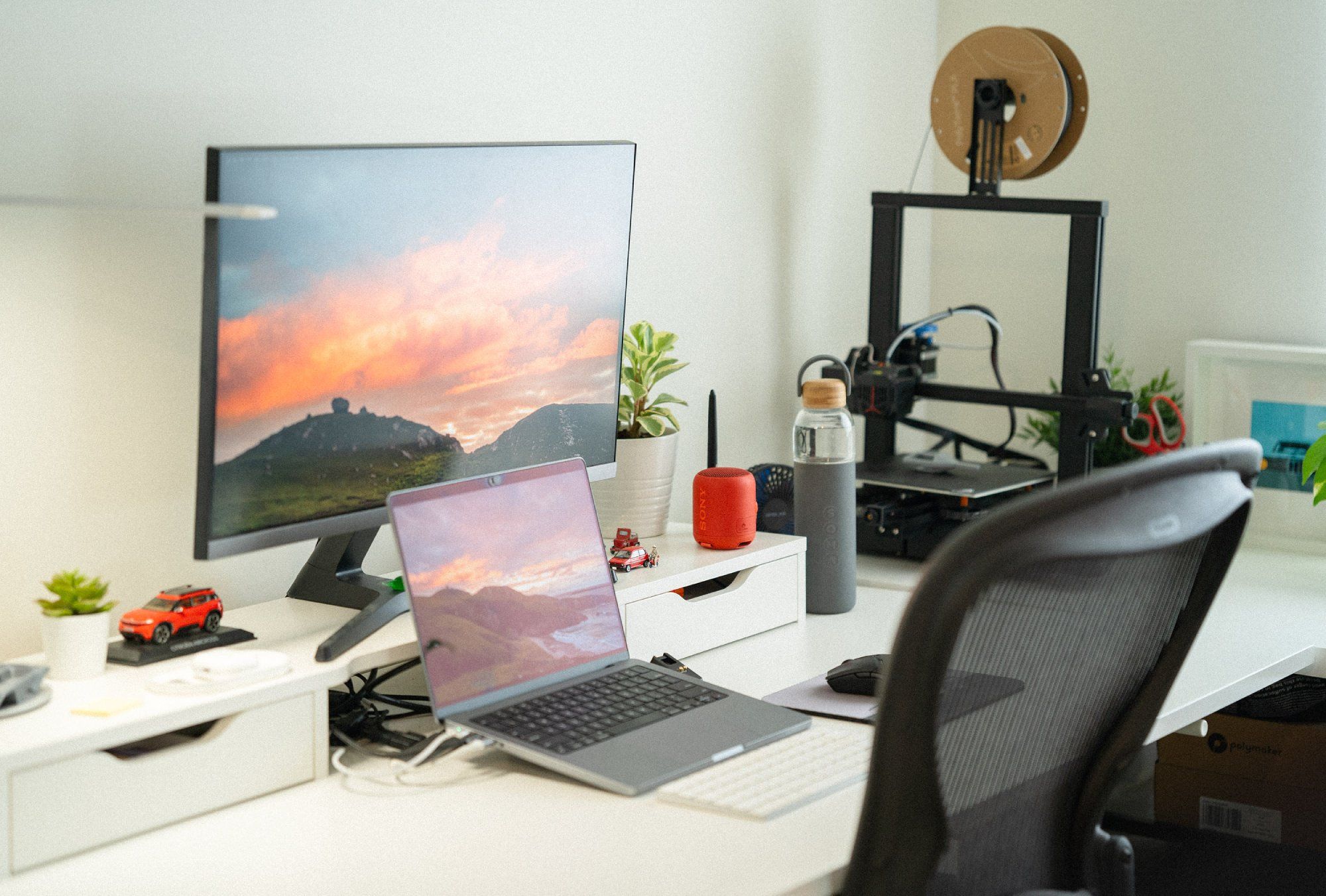 A home office desk setup with a Samsung 4K monitor and a MacBook Pro