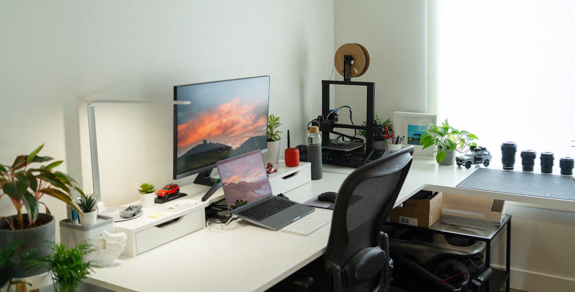 A corner desk setup by the window in a designer’s home office