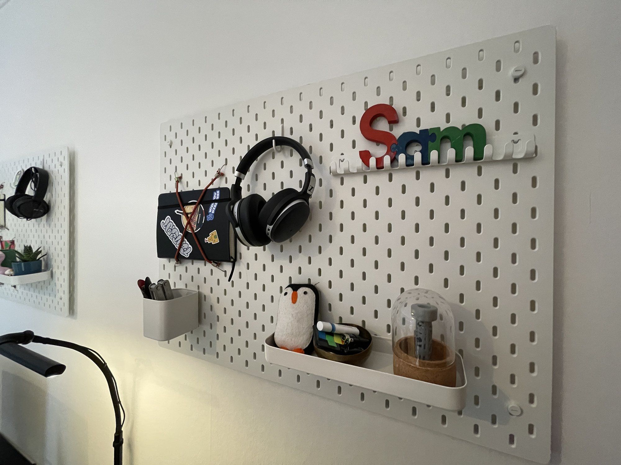 Two pegboards on the wall, neatly holding headphones, stationery, and various decor elements