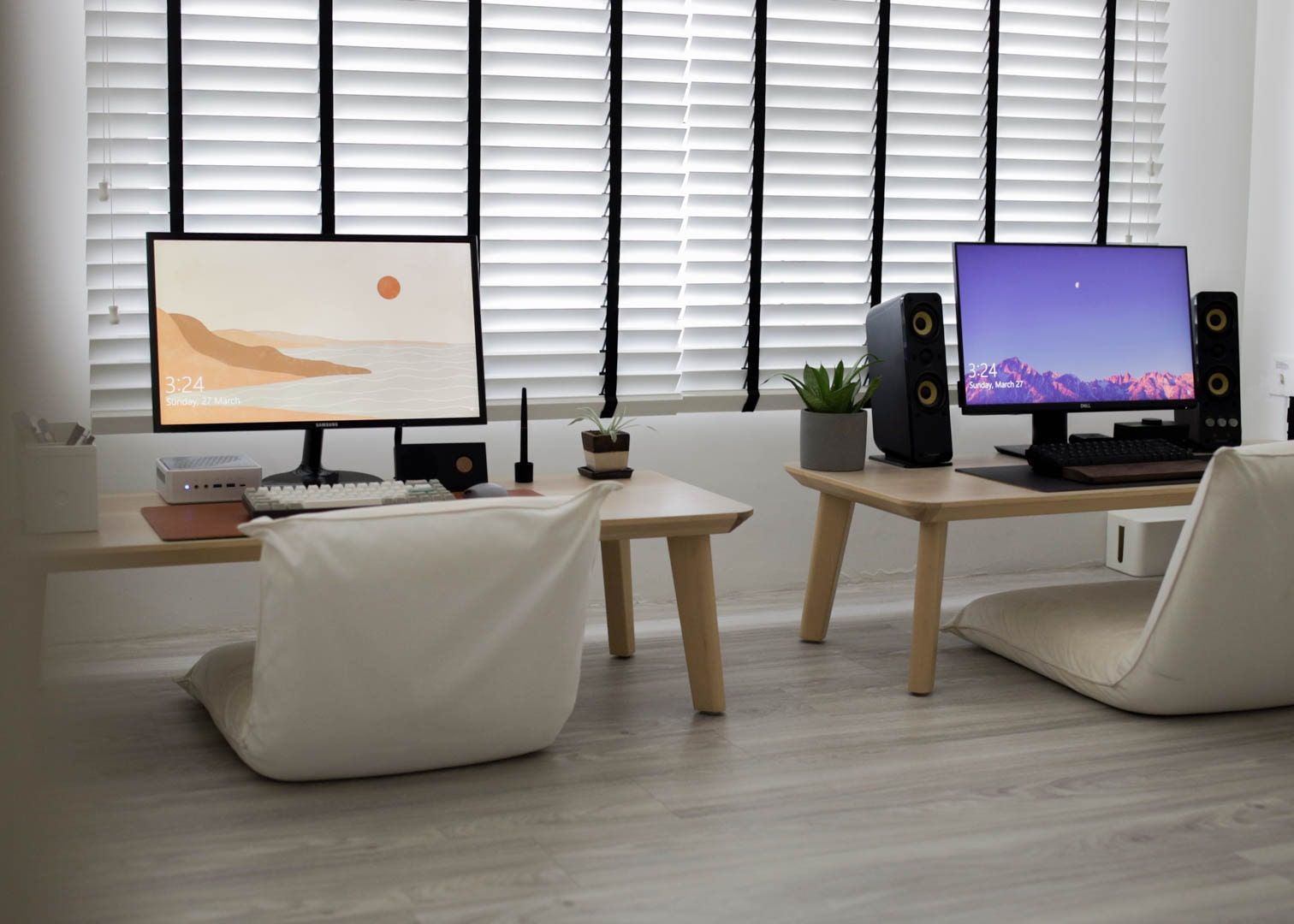 A minimalist workspace with a Japanese aesthetic, featuring dual monitors on wooden stands, floor chairs, and a peaceful atmosphere accentuated by natural light