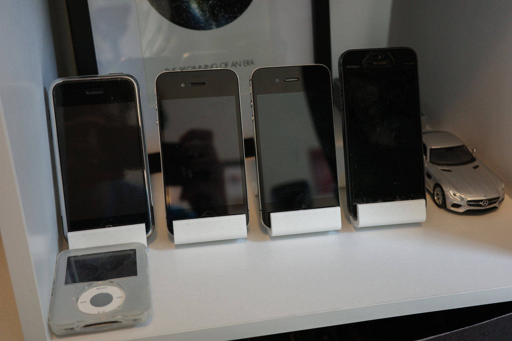 A collection of Apple mobile devices, namely iPhones, lined up in chronological order from left to right