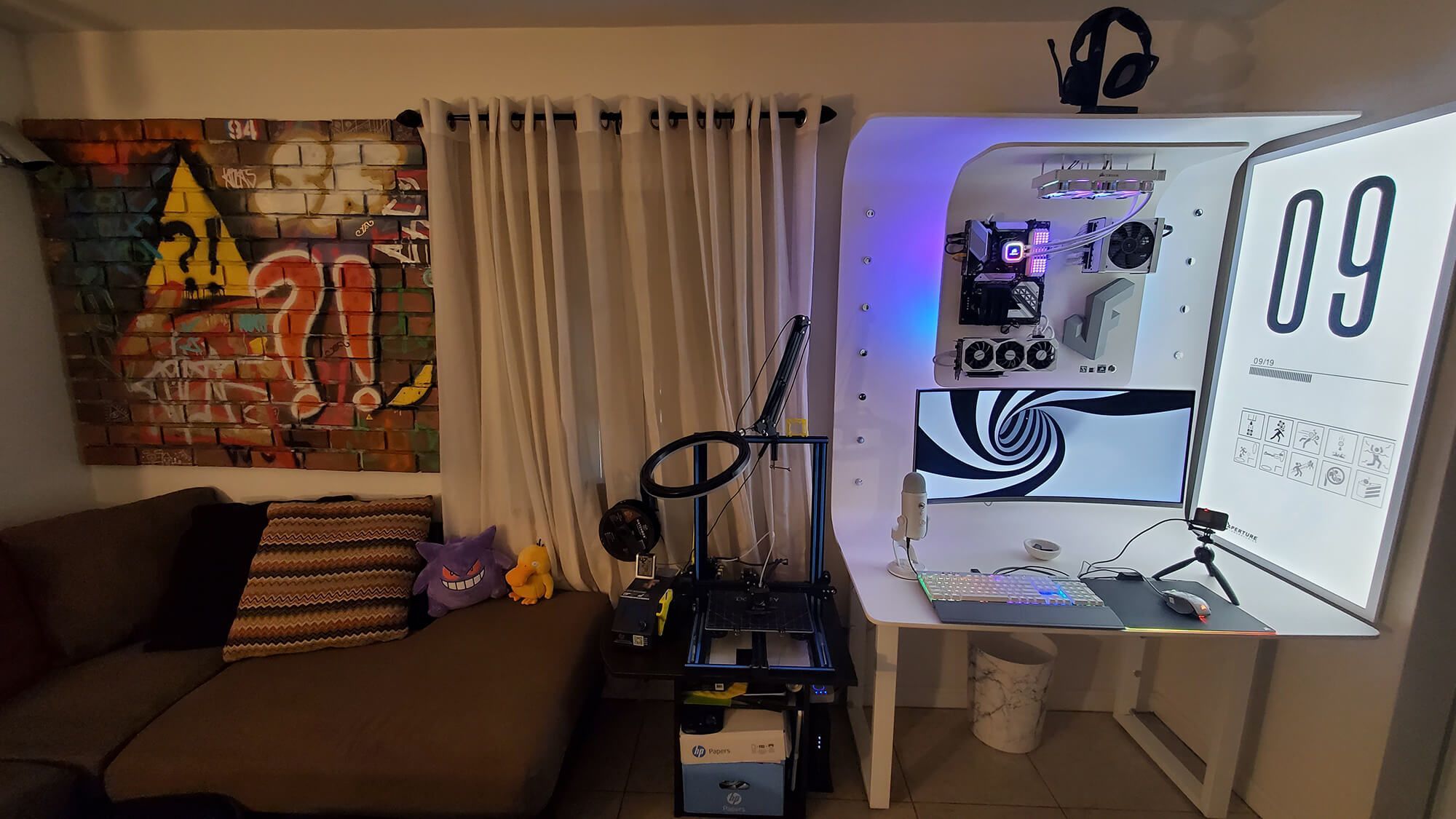 A DIY minimalist battlestation in Florida, with a large monitor, PVC piping desk, 3D printer setup, ambient lighting, and a graffiti art backdrop.