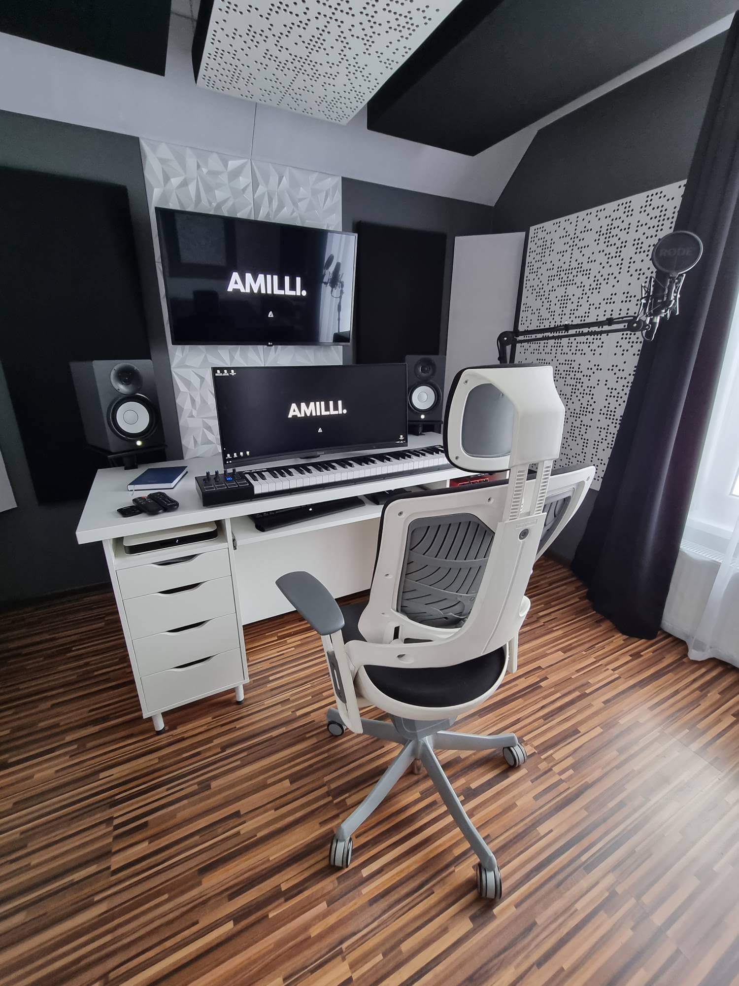 A minimalist music production desk setup in Kraków, Poland, featuring studio monitors, a keyboard, a microphone, and acoustic panels