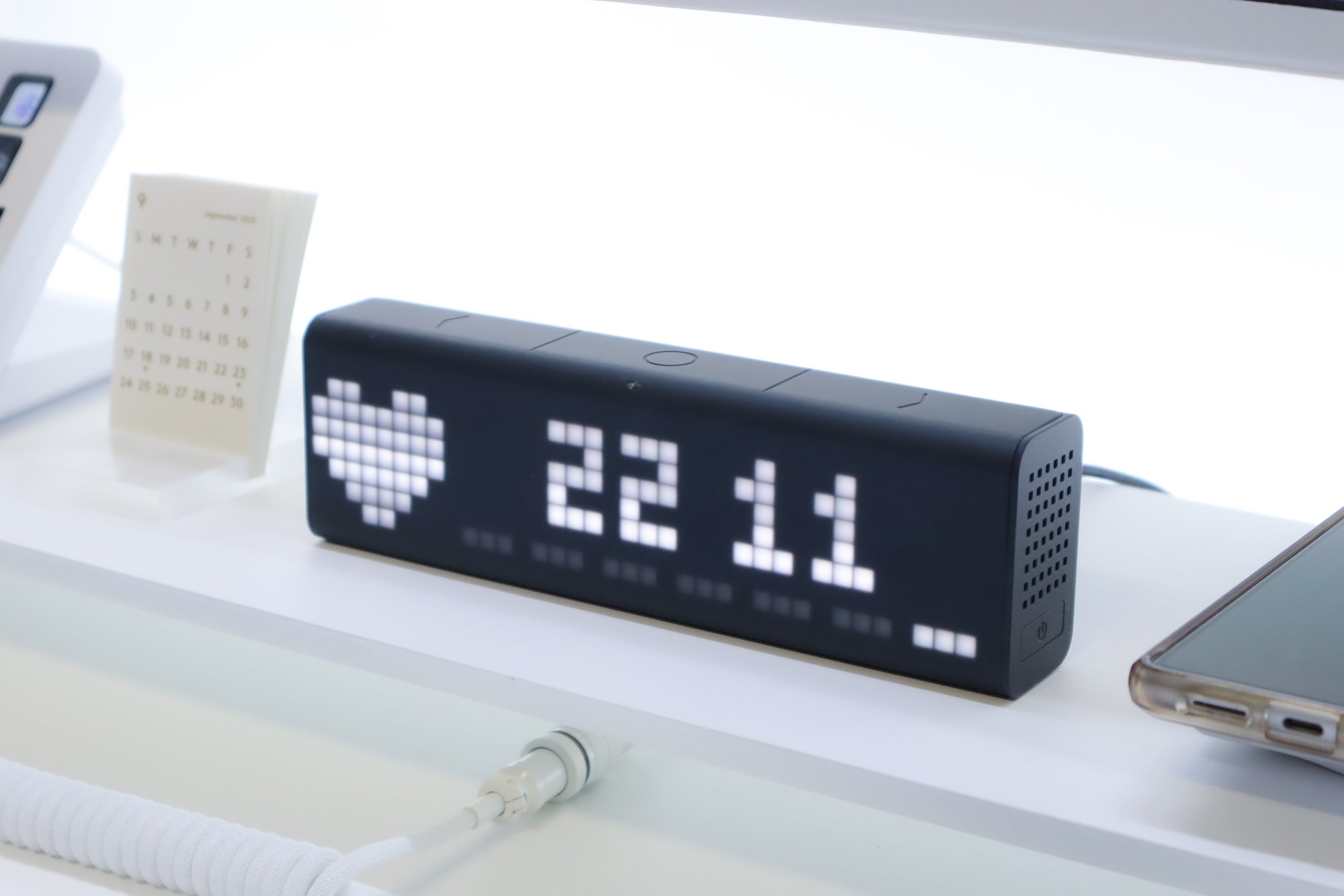 A modern LaMetric Time digital clock displaying the time in large white LED numerals, with a minimalistic design