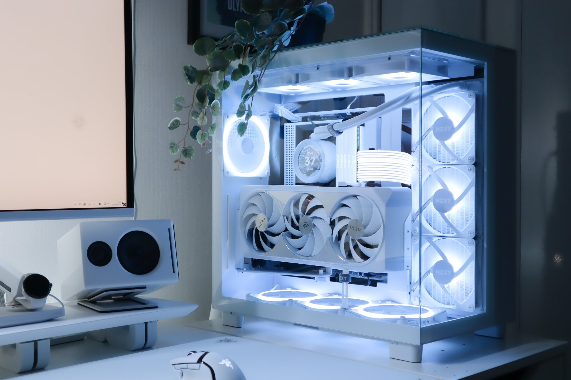 A high-end custom PC build with a clear glass case, showcasing white components and LED fans, alongside a sleek desktop setup with matching white peripherals, complemented by ambient blue lighting