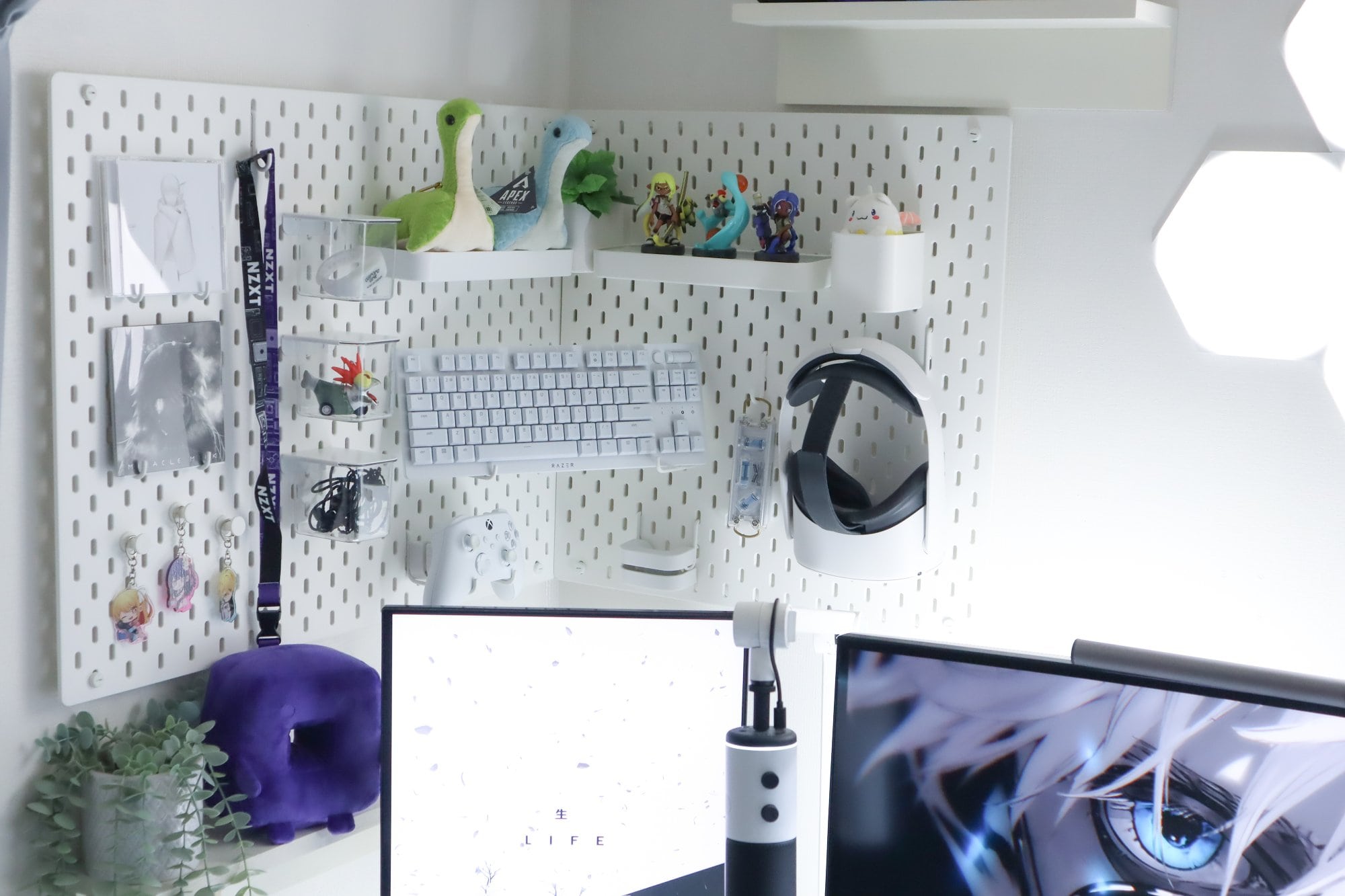 A creative home workspace corner with white pegboards organising various items such as a mechanical keyboard, gaming headset, and collectible figurines