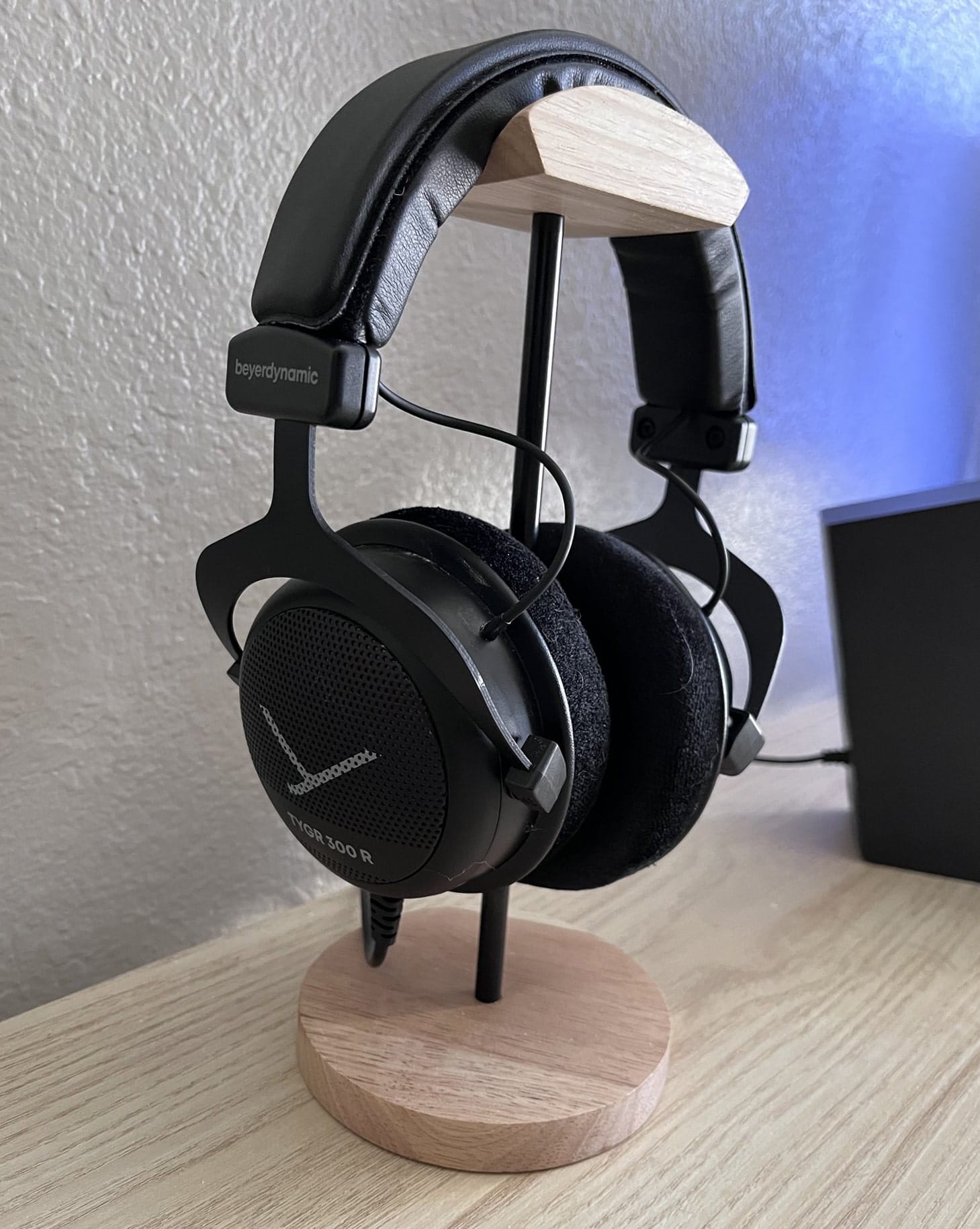 Black open-back headphones from beyerdynamic resting on a wooden stand on a desk