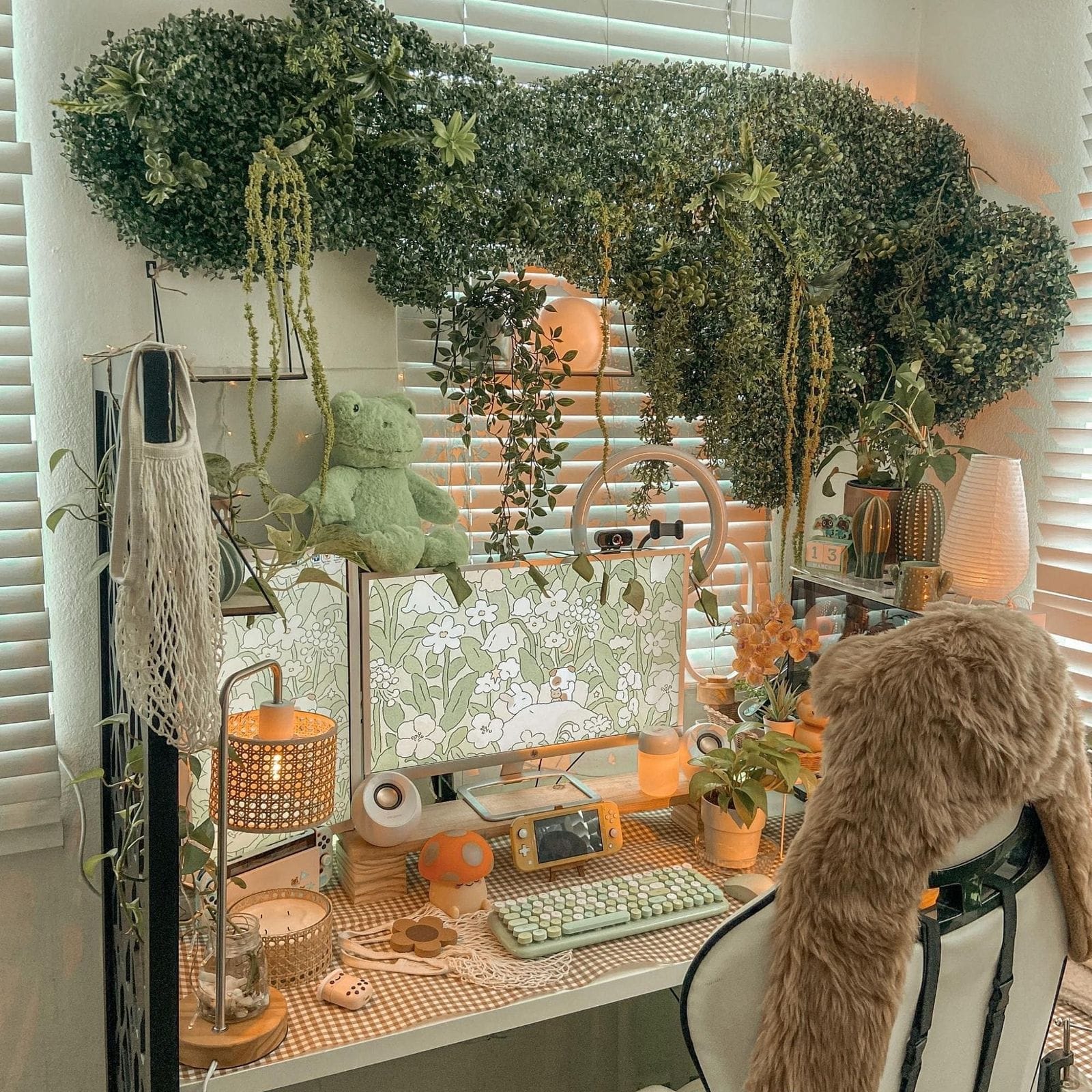  A cosy, Studio Ghibli-inspired workspace featuring an array of potted plants, decorative vines overhead, whimsical ornaments, and gaming console on a desk. A faux fur hat adorn the chair