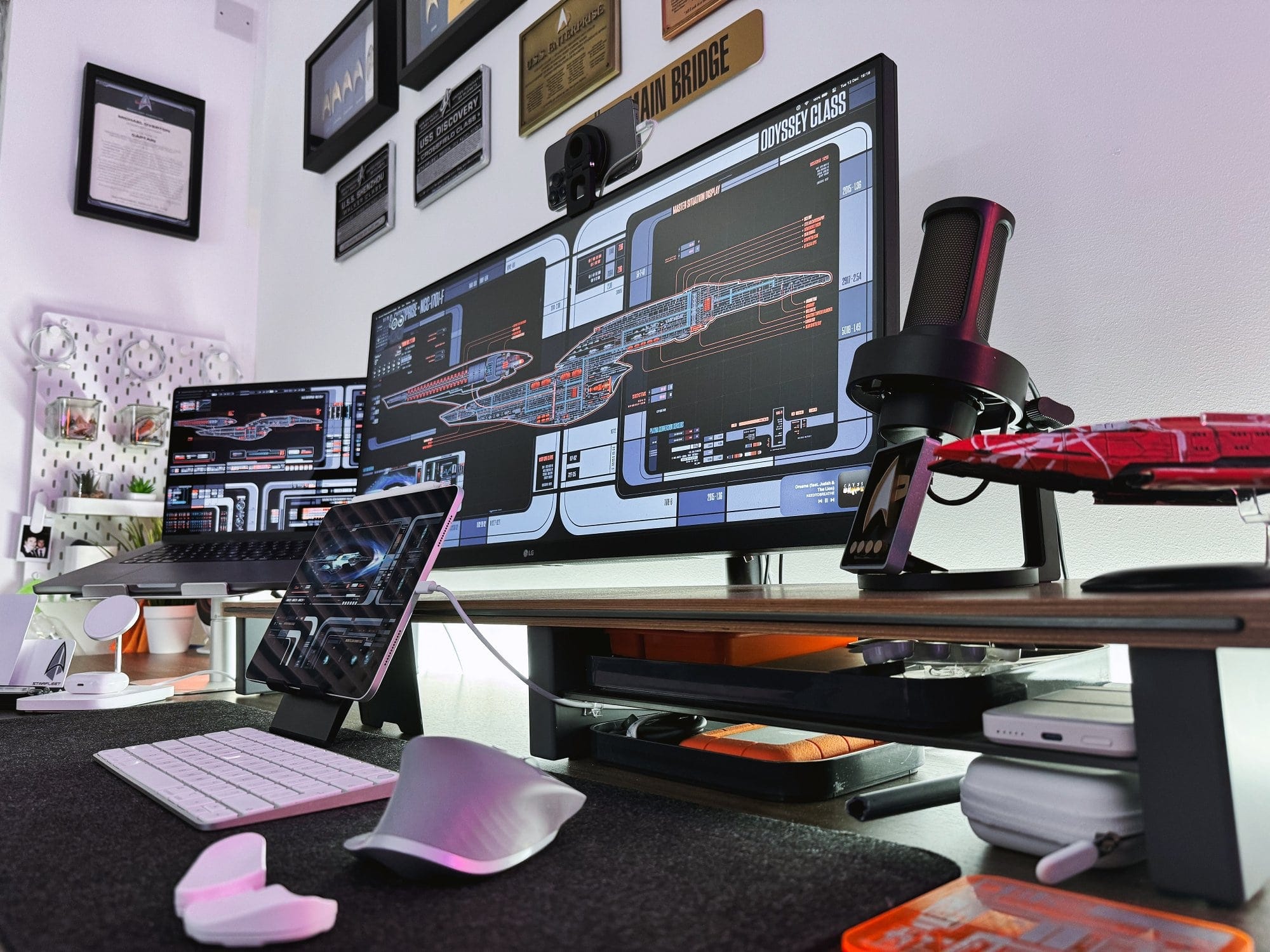 A detailed view of a desk with high-tech equipment, featuring Star Trek schematics, with Star Trek-themed decorative plaques on the wall above