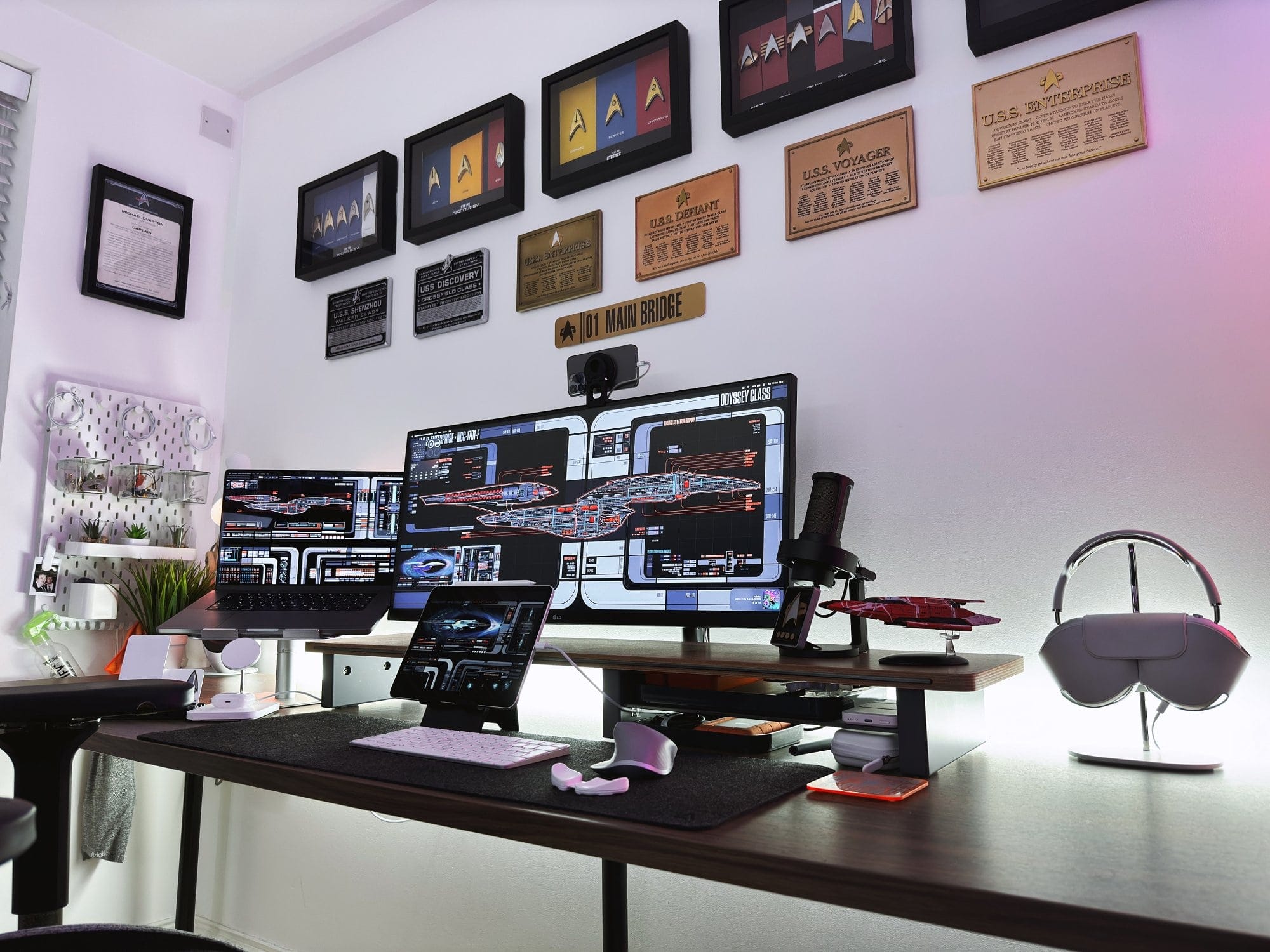 A sophisticated workstation with multiple screens and Star Trek memorabilia on the wall