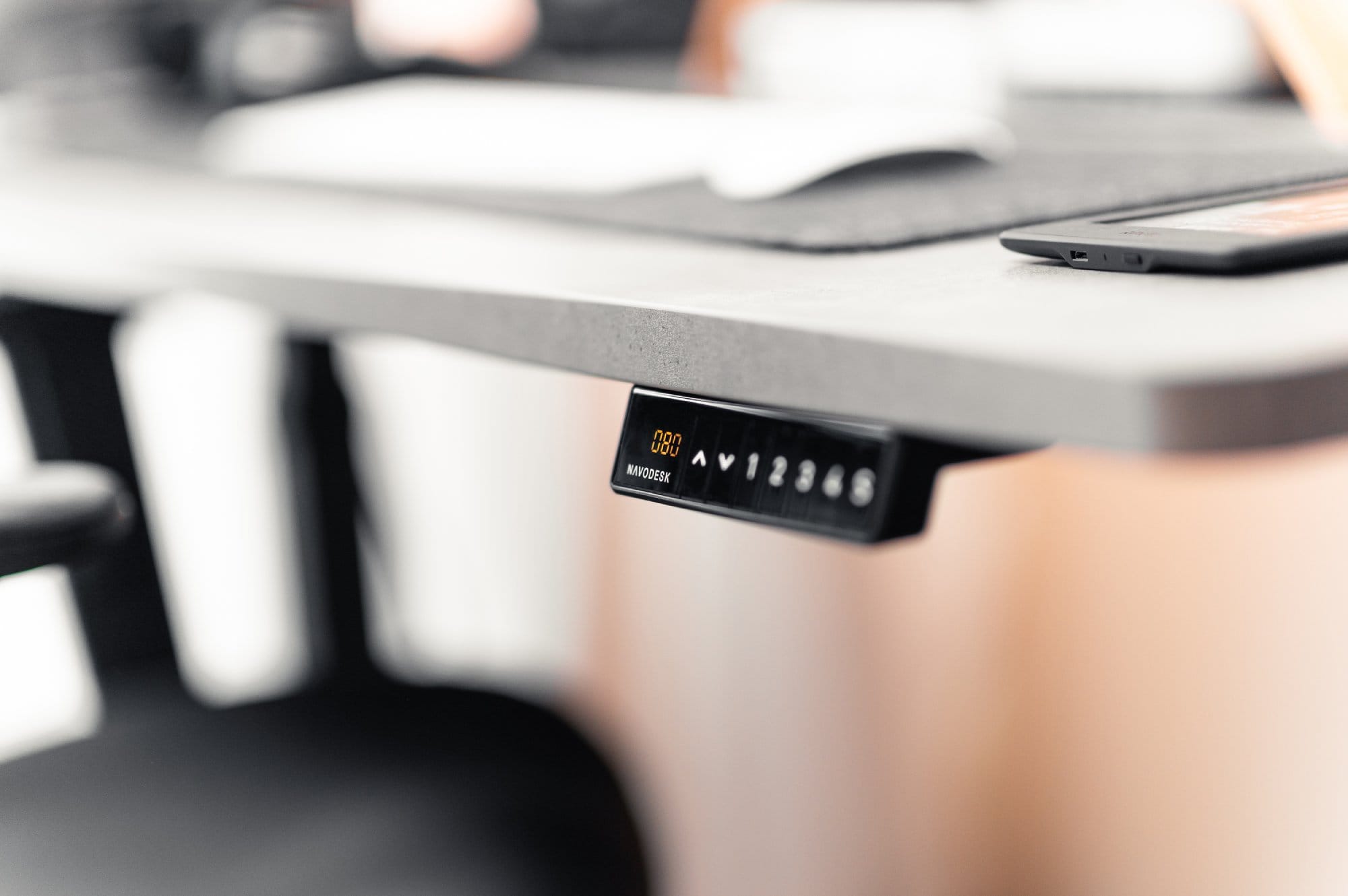  A close-up view of a desk’s edge showing the control panel with height indicators of an adjustable standing desk