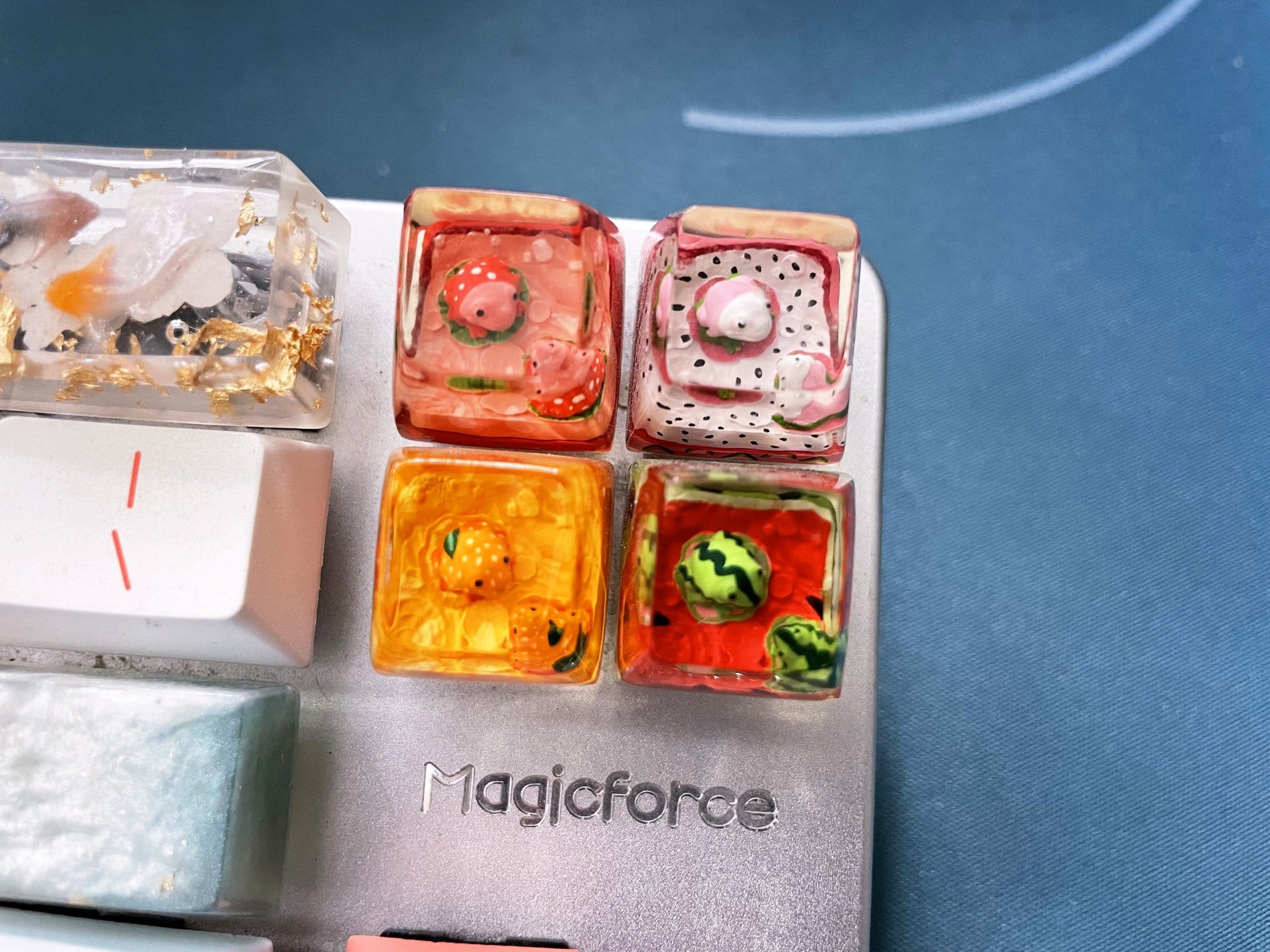 A closer view of a mechanical keyboard with custom, colourful, transparent keycaps with miniature frogs and fish embedded within them