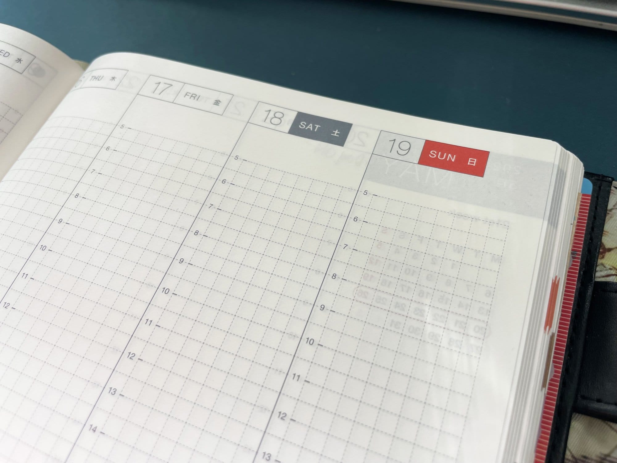 An open planner displaying an empty weekly schedule grid with Sunday highlighted in red