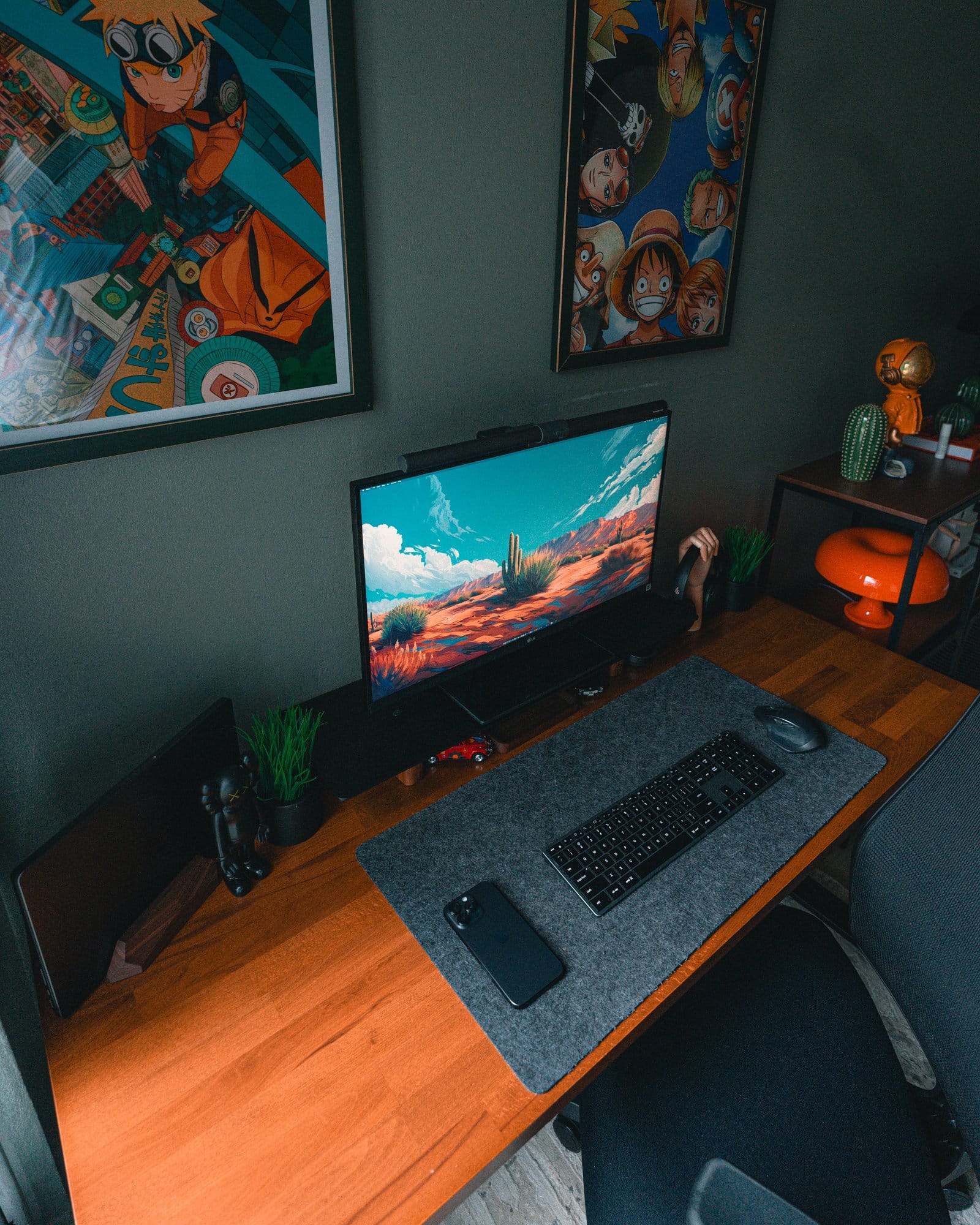 A modern desk setup with an LG 27" 27BN88U-B Ergo monitor, the BenQ Halo LightBar, the 14" M3 MacBook Pro, the Edifier W820NB headphones, the Edifier R1700BTS speakers, the Satechi Slim X3 keyboard, the Logitech MX Master 2S mouse, and a Hexcal desk mat, complemented by anime posters of Naruto and One Piece on the wall, and a small shelf with an orange mushroom lamp and astronaut figurine