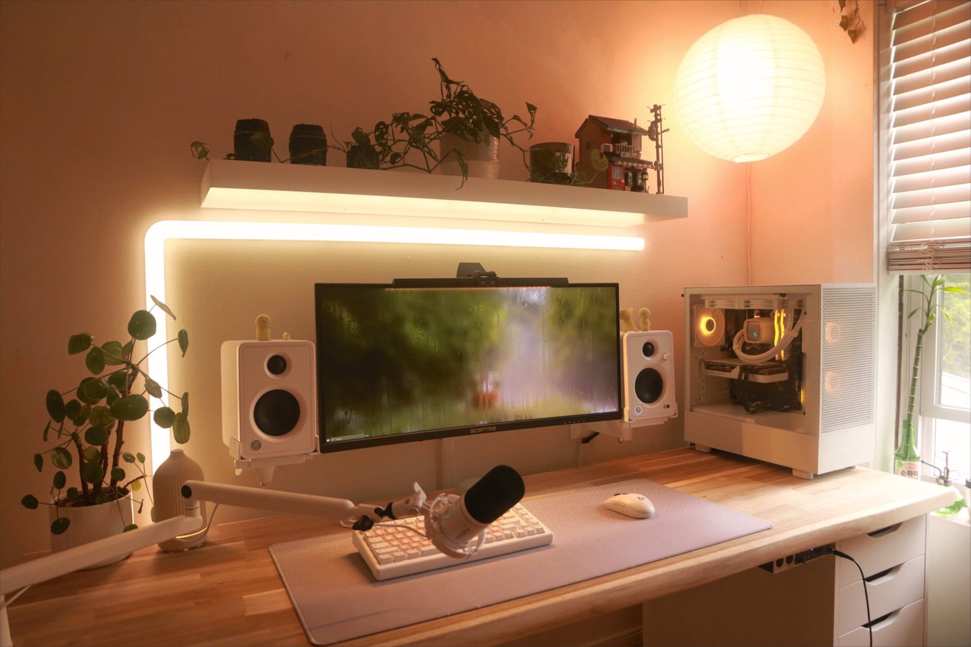 A stylish desk setup featuring a Sceptre 30″ Ultrawide monitor with EJITILAI Motion Sensor light bar, Mackie CX3 speakers, AKKO MOD 007 PC keyboard, Logitech G305 mouse, and Logitech Brio webcam, all illuminated by a soft ambient light