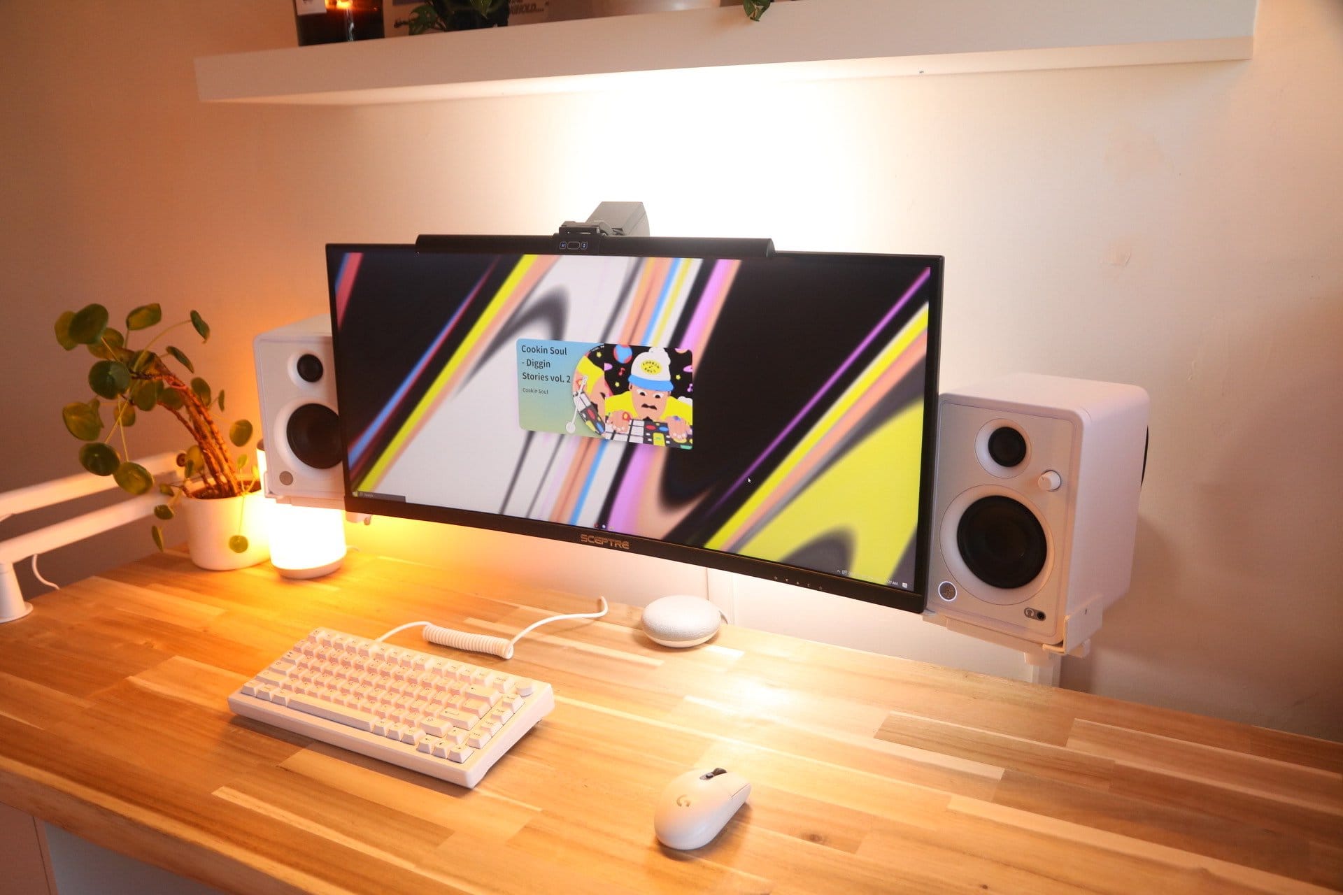 A clean and modern computer setup featuring a Sceptre 30″ Ultrawide monitor with an EJITILAI Motion Sensor light bar, Mackie CX3 speakers, AKKO MOD 007 PC keyboard, and Logitech G305 mouse, all arranged on a wooden desk