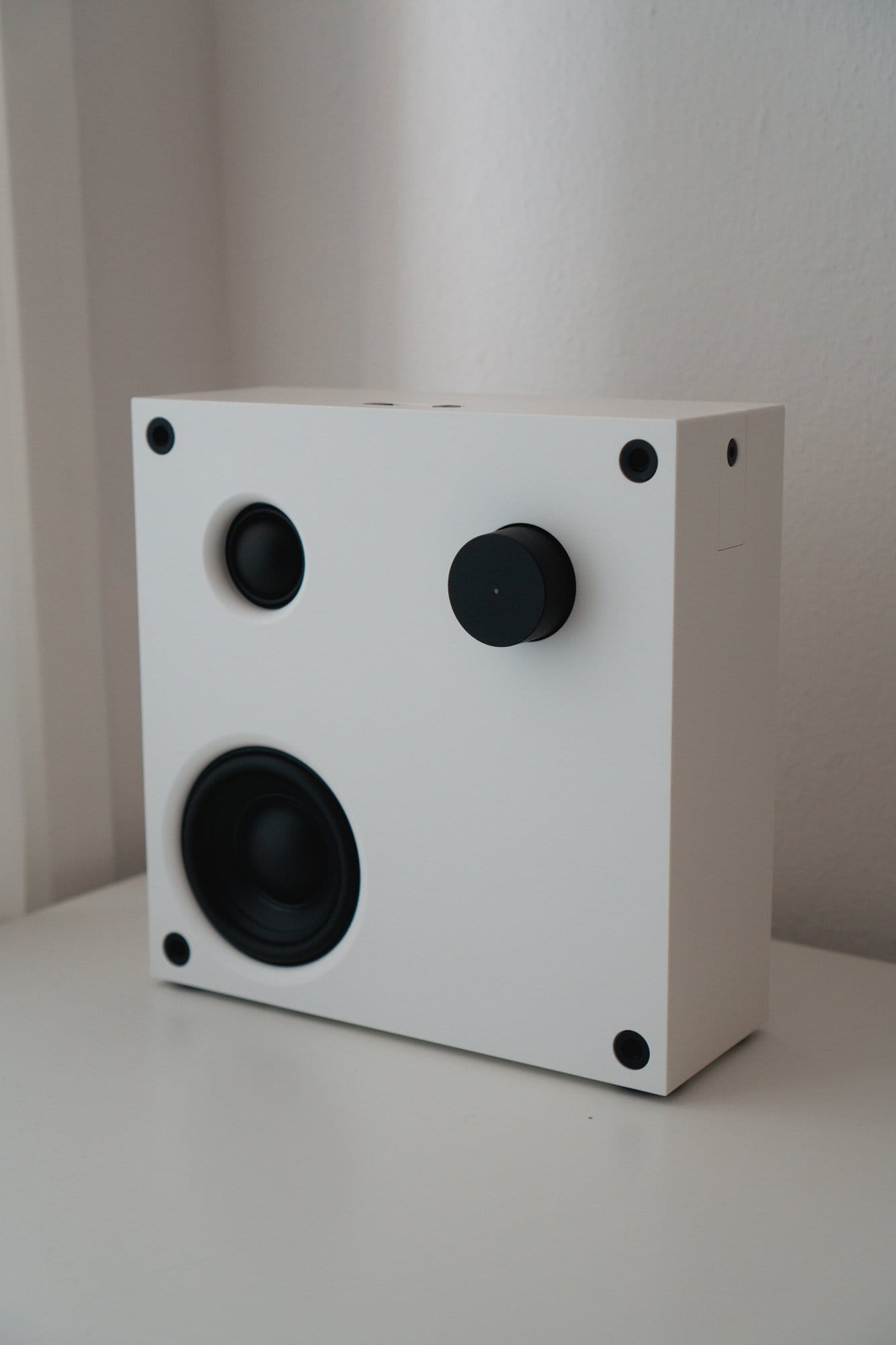 A close-up of an IKEA VAPPEBY speaker on a white desk