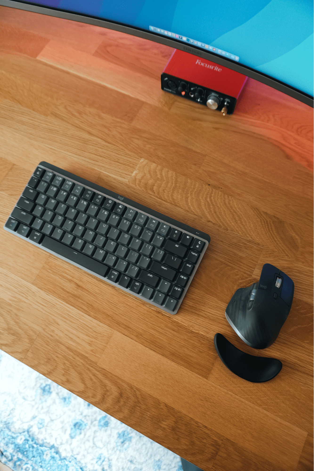 A Logitech MX Mechanical Mini keyboard and MX Master 3S mouse on an IKEA KARLBY oak desk, with a Focusrite audio interface and Samsung LU32R590CWNXZA monitor in view