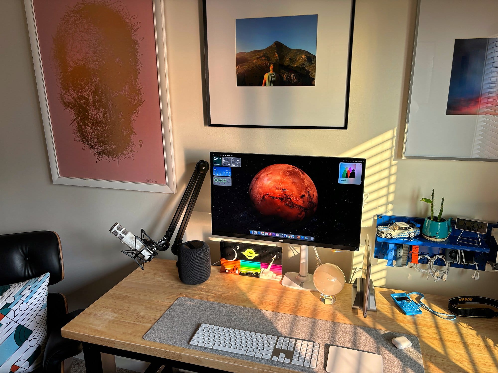 A home office setup with an LG 27″ IPS 4K UHD monitor, a RØDE Podcaster microphone on a RØDE PSA1 boom arm, an Apple Magic Keyboard, an Apple Magic Trackpad, and a BeaverPeak Felt Desk Pad on a wooden desk
