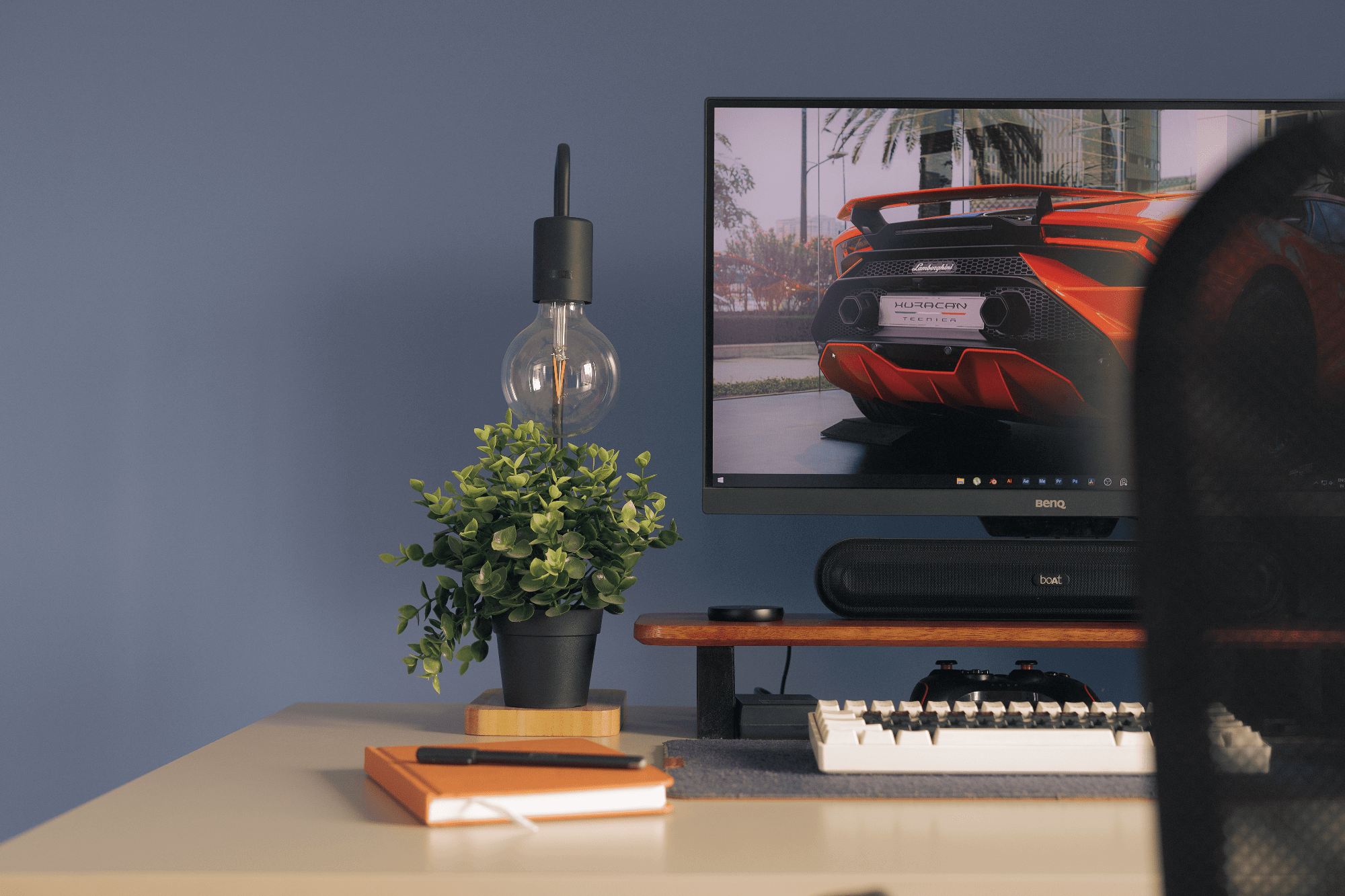 A desk setup with a BenQ PD2500Q monitor, an EPOMAKER Skyloong SK61 keyboard, and an IKEA TVÄRHAND lamp next to an IKEA FEJKA plant
