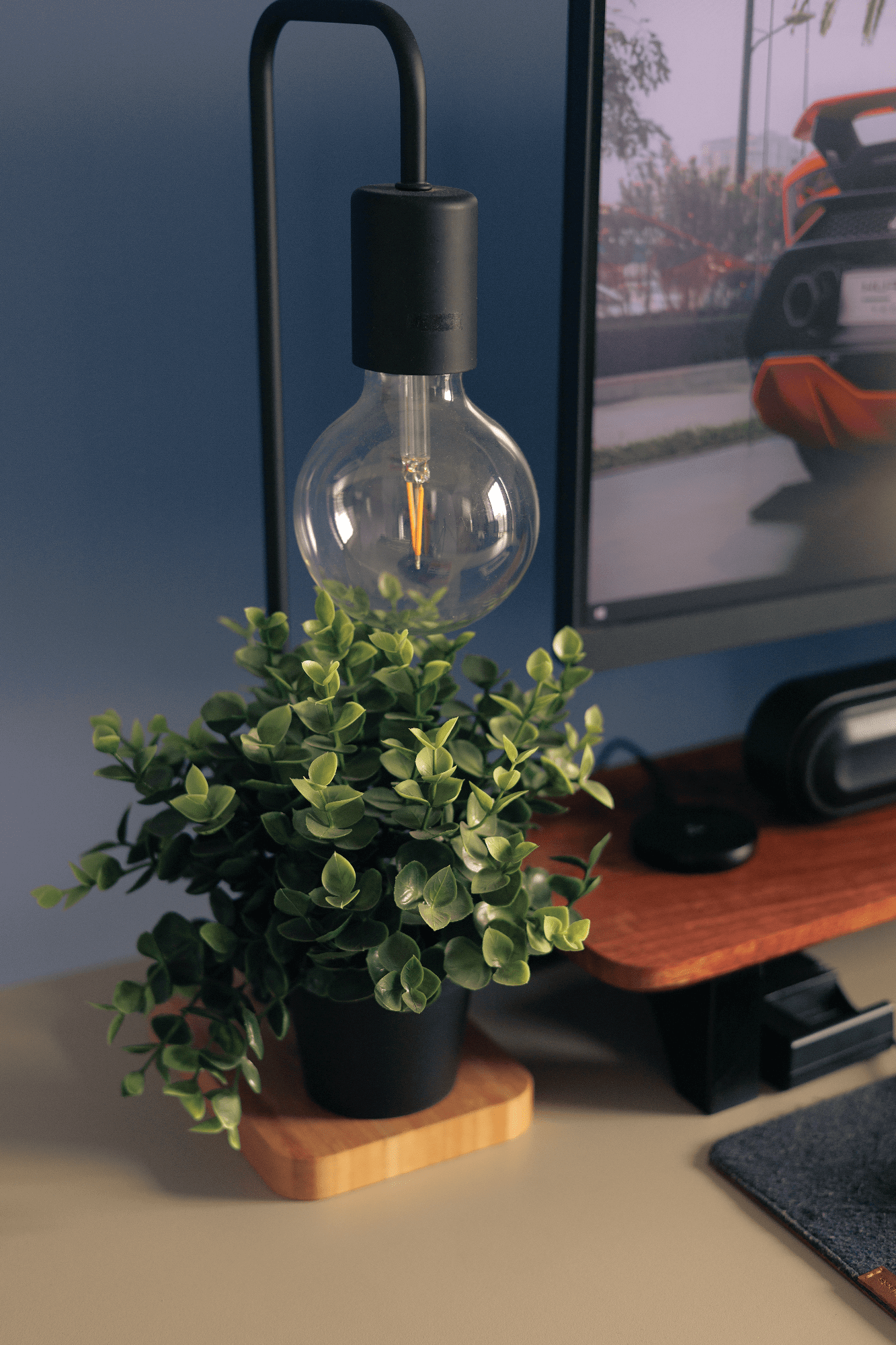 A desk corner with an IKEA TVÄRHAND lamp and an IKEA FEJKA plant beside a BenQ PD2500Q monitor