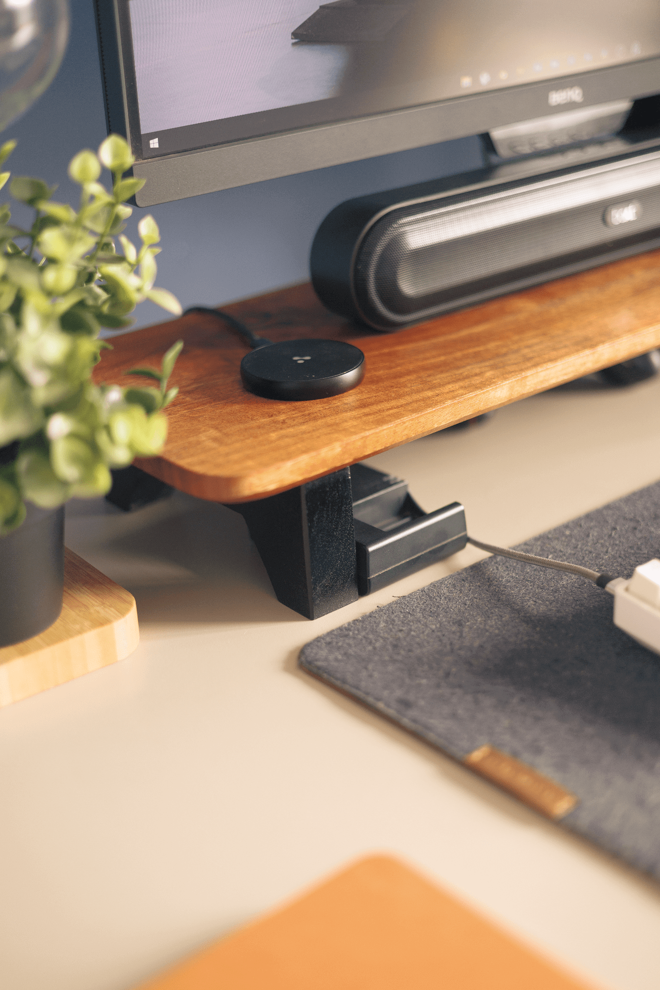 A desk shelf with a boAt Aavante Bar 490 speaker, an Ambrane MagSafe charger, and a BenQ PD2500Q monitor above a DailyObjects desk mat