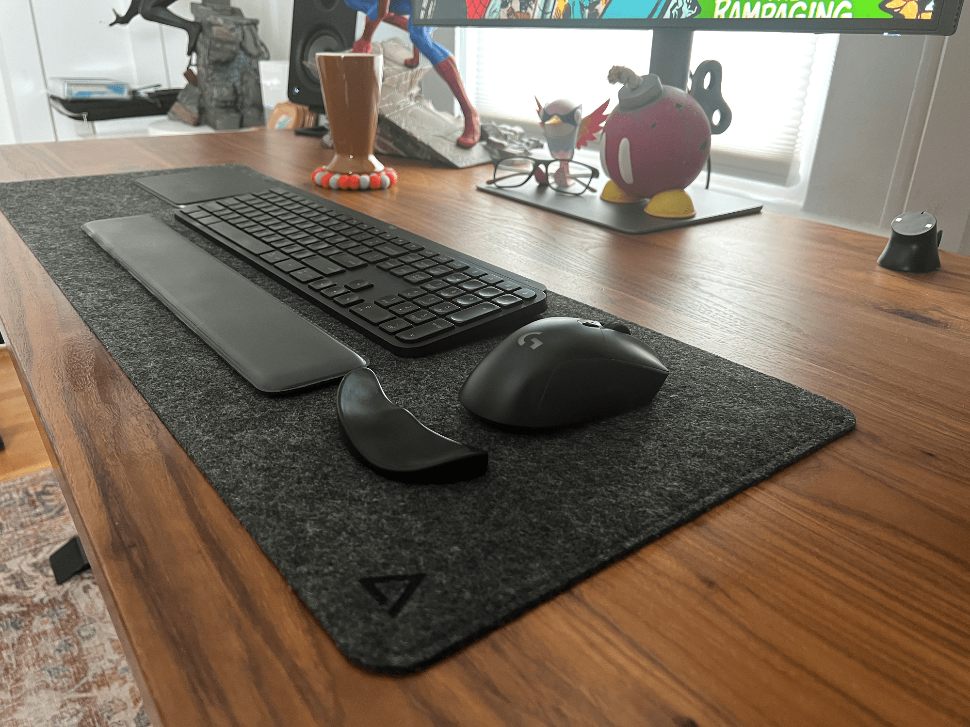 A wooden desk with Logitech G703 mouse, Deltahub felt mat and Aten wrist rest