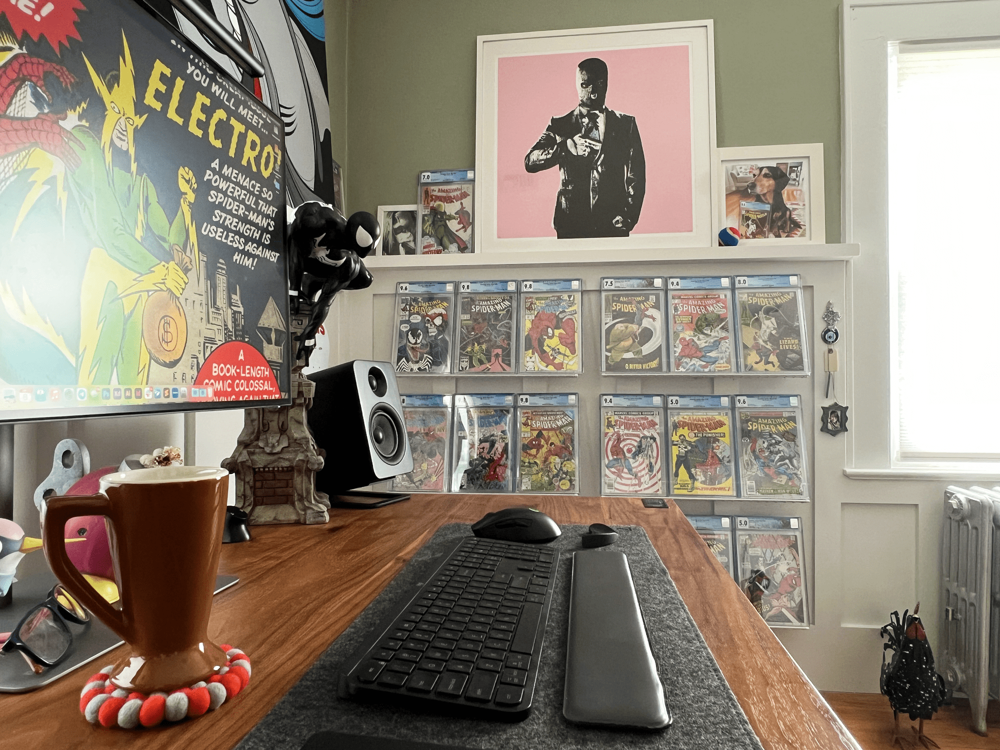 A home workspace with Spider-Man comics, framed art and a BenQ monitor on a wooden desk