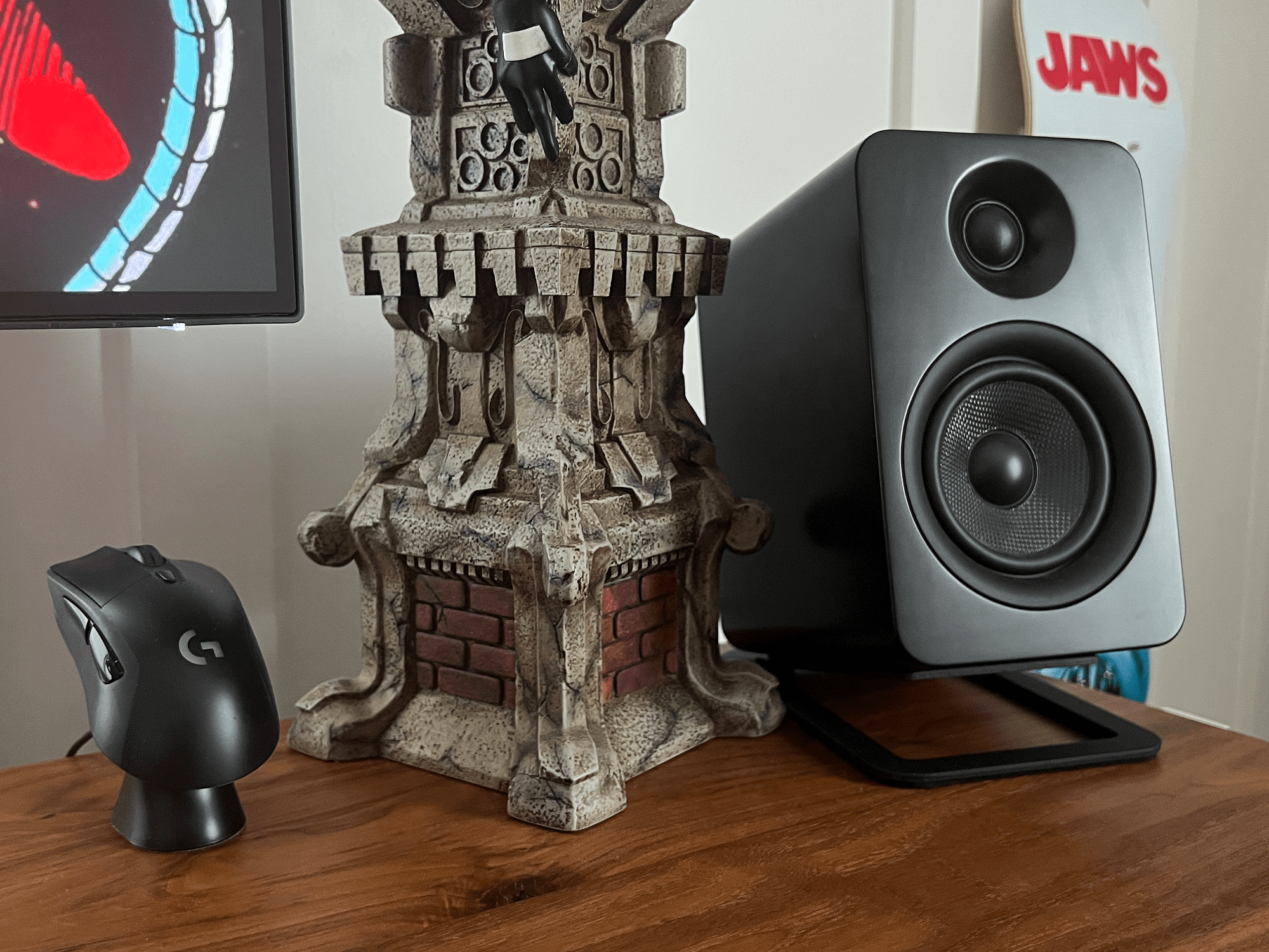 A desktop with a Logitech G703 mouse, Kanto YU4 speaker and superhero figurine on a stone-style base
