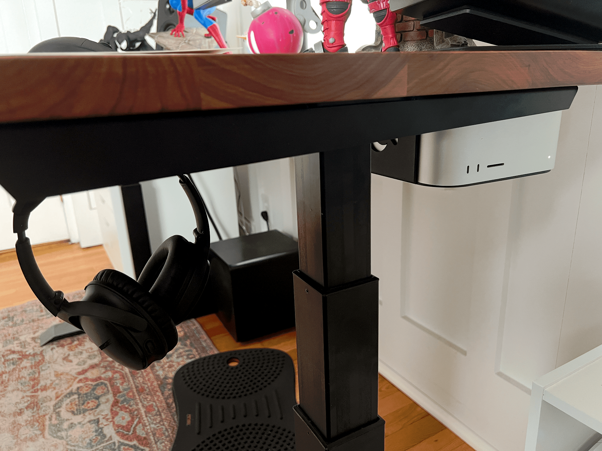 A Bose QuietComfort headset and Apple Mac Studio mounted under a wooden desk