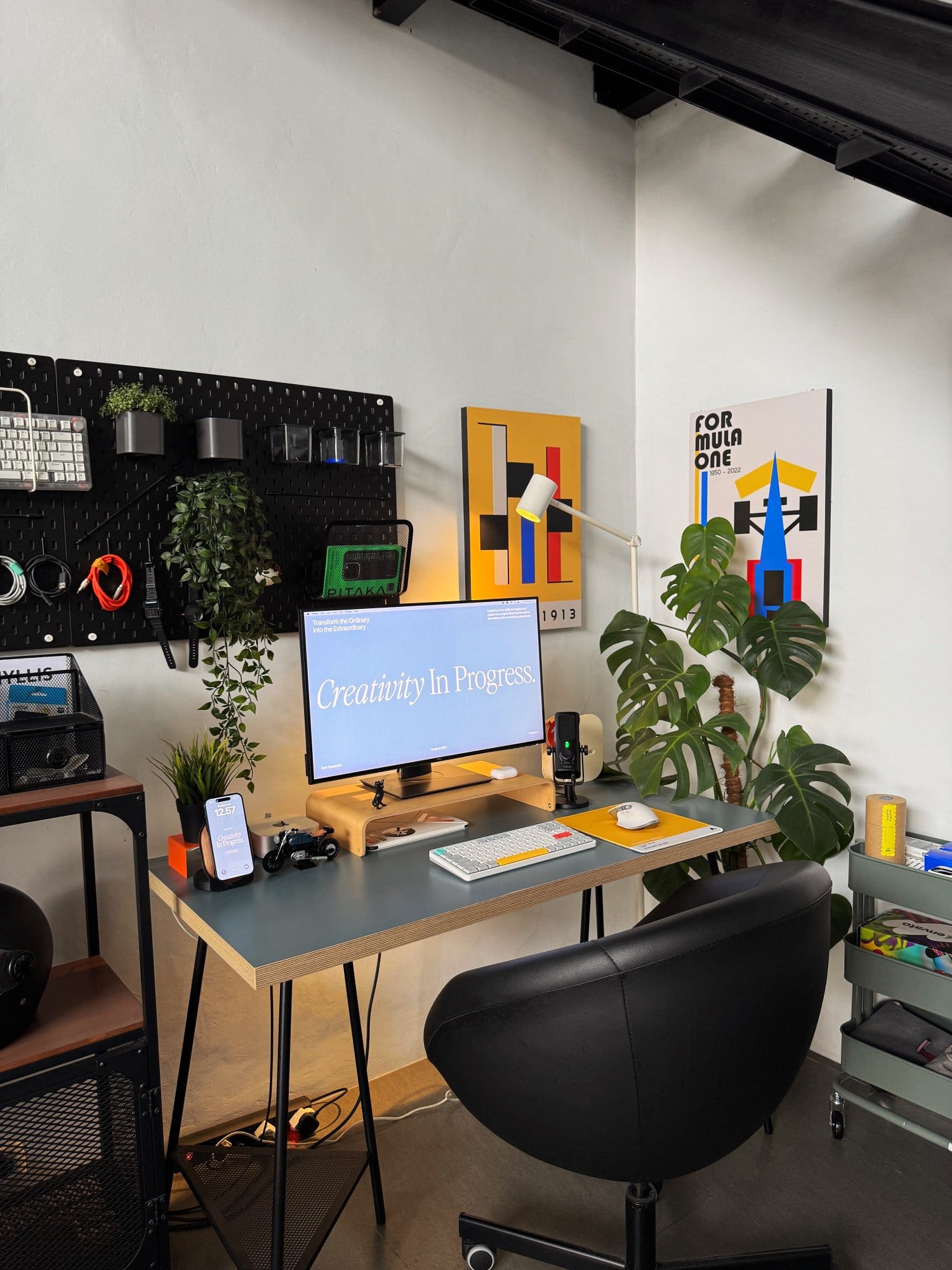 modern workspace featuring a clean desk setup with a monitor, keyboard, plants, and wall art