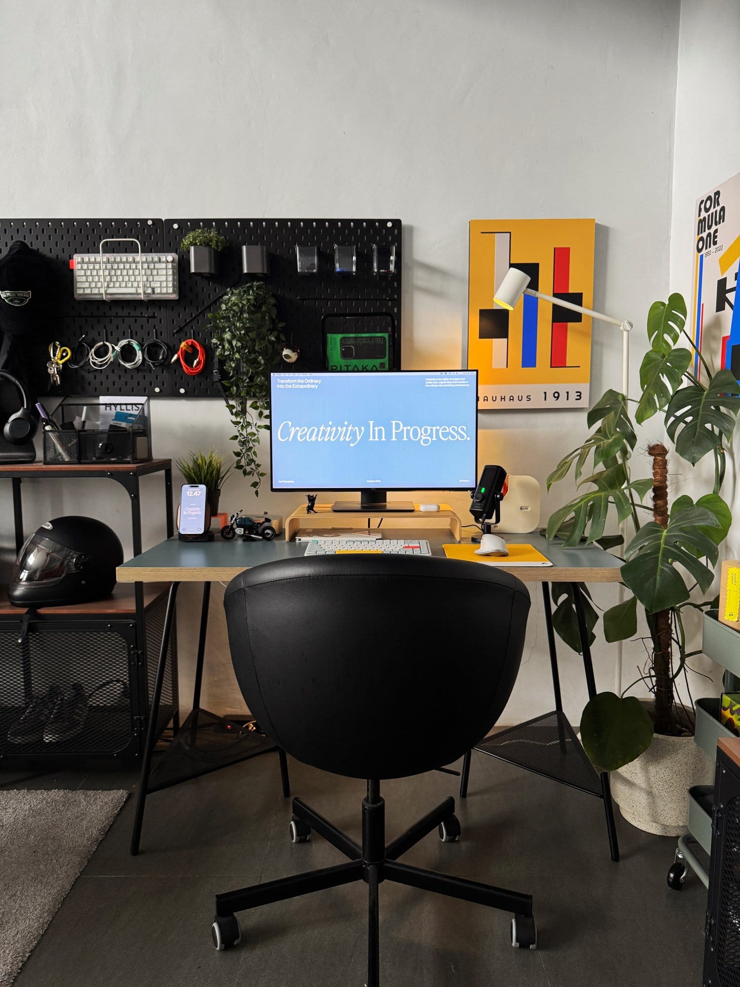 modern workspace featuring a clean desk setup with a monitor, keyboard, plants, and wall art