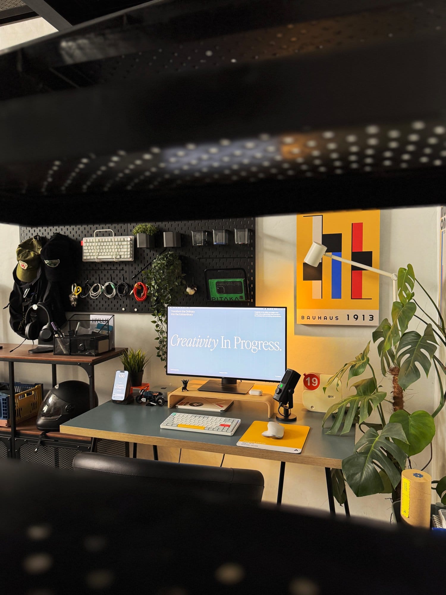 modern workspace featuring a clean desk setup with a monitor, keyboard, plants, and wall art