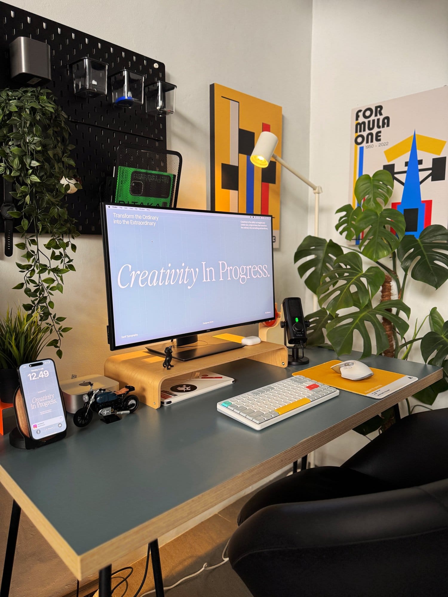 modern workspace featuring a clean desk setup with a monitor, keyboard, plants, and wall art