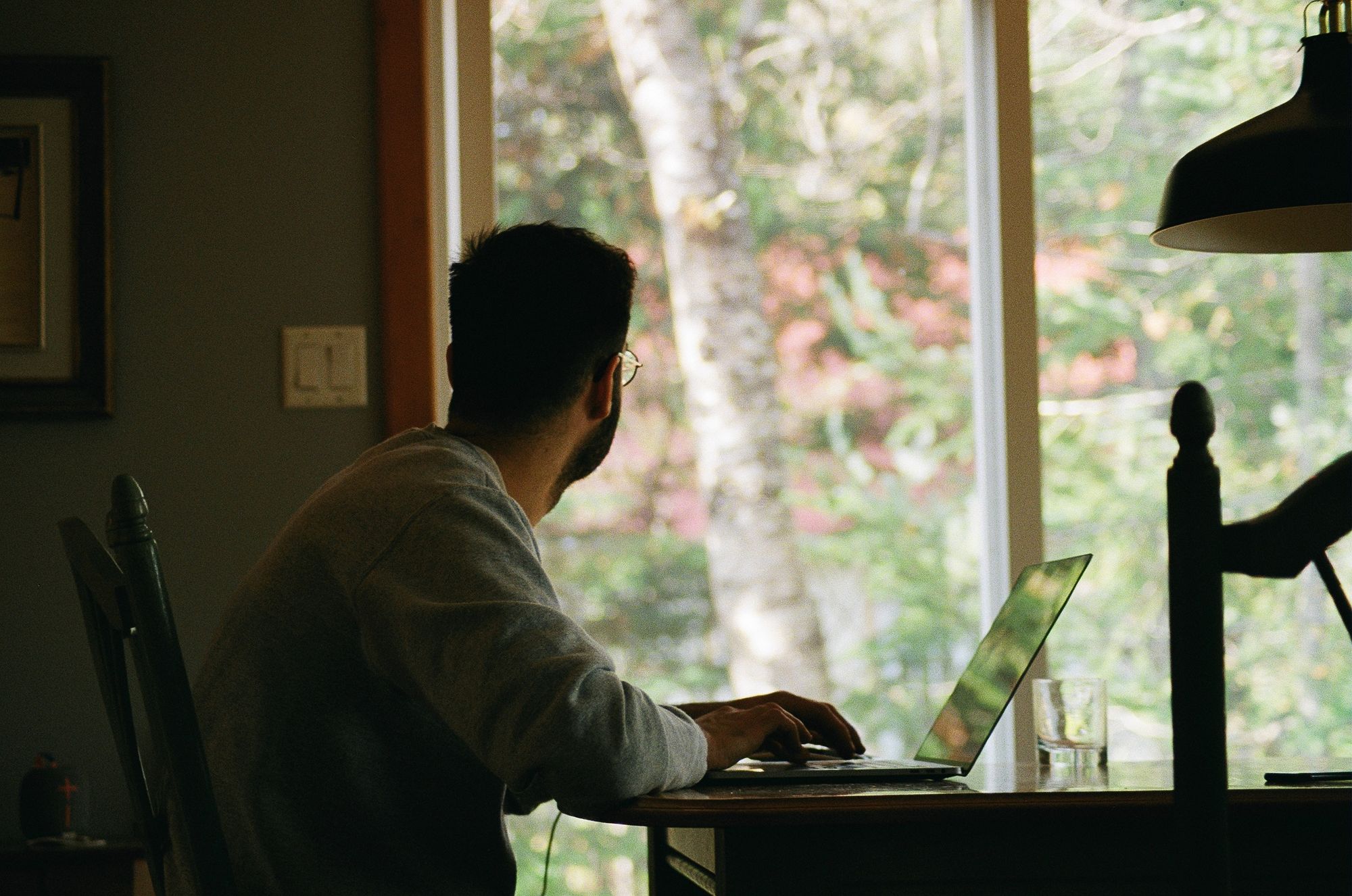 A person working in a home office with a view of greenery through a window, embodying a serene work environment