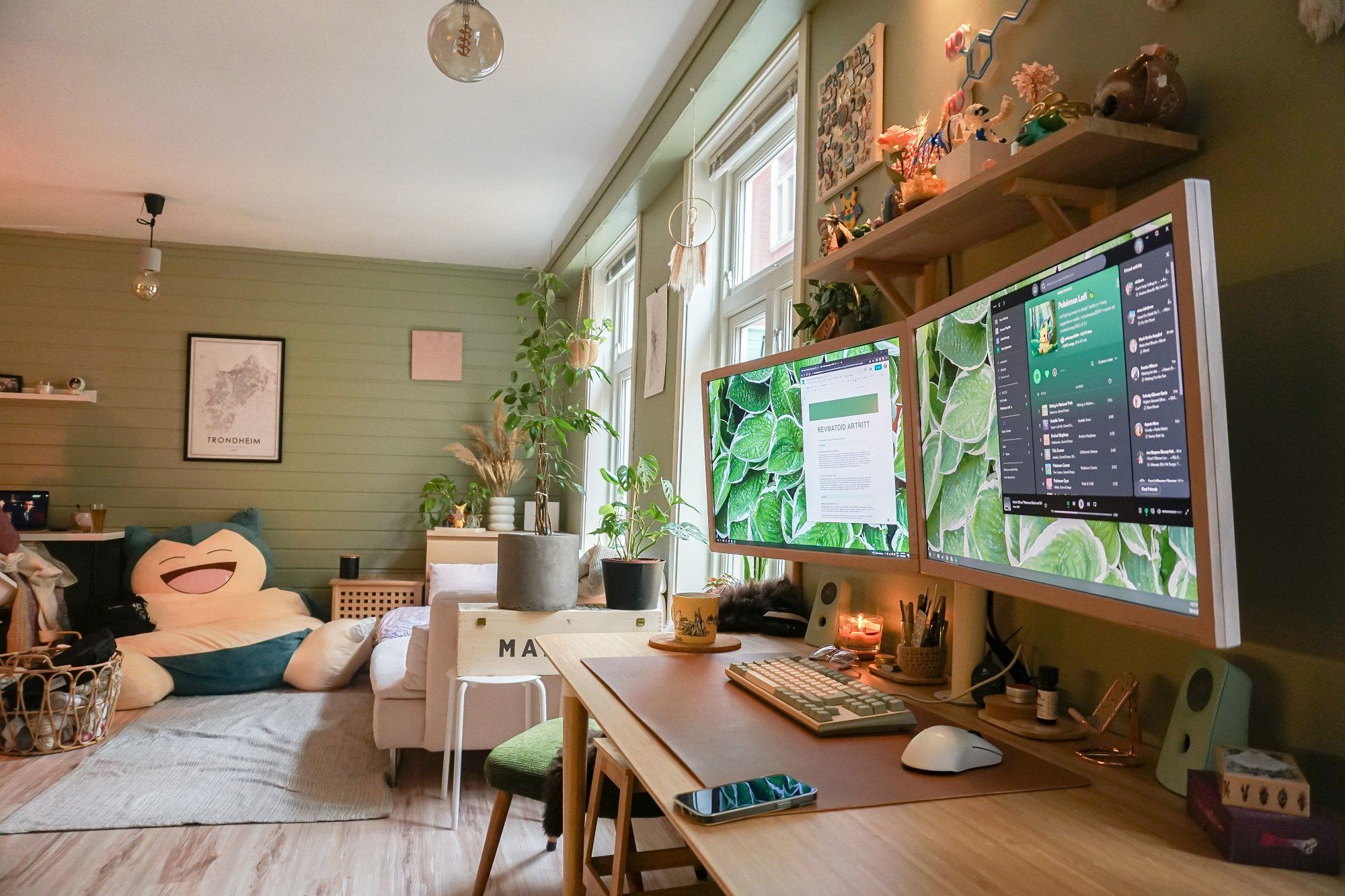 A cosy desk setup with two monitors and a living room with a huge Snorlax plush toy that serves as a bean bag for and a dog bed
