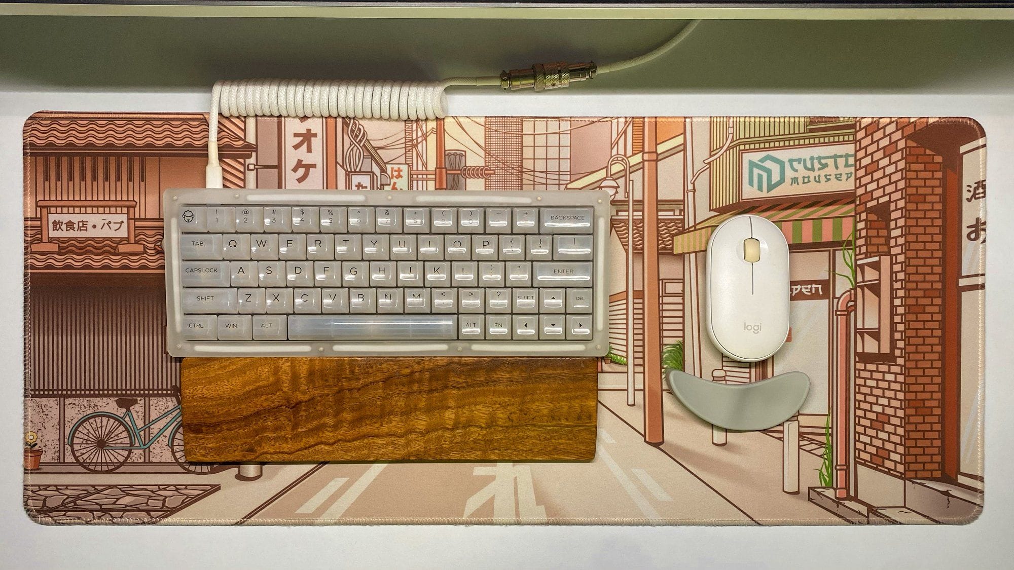 A custom Akko ACR64 keyboard with transparent keycaps and Gateron Milky Yellow switches, accompanied by a Logitech Pebble M350 mouse on an illustrated desk mat featuring a Japanese street scene