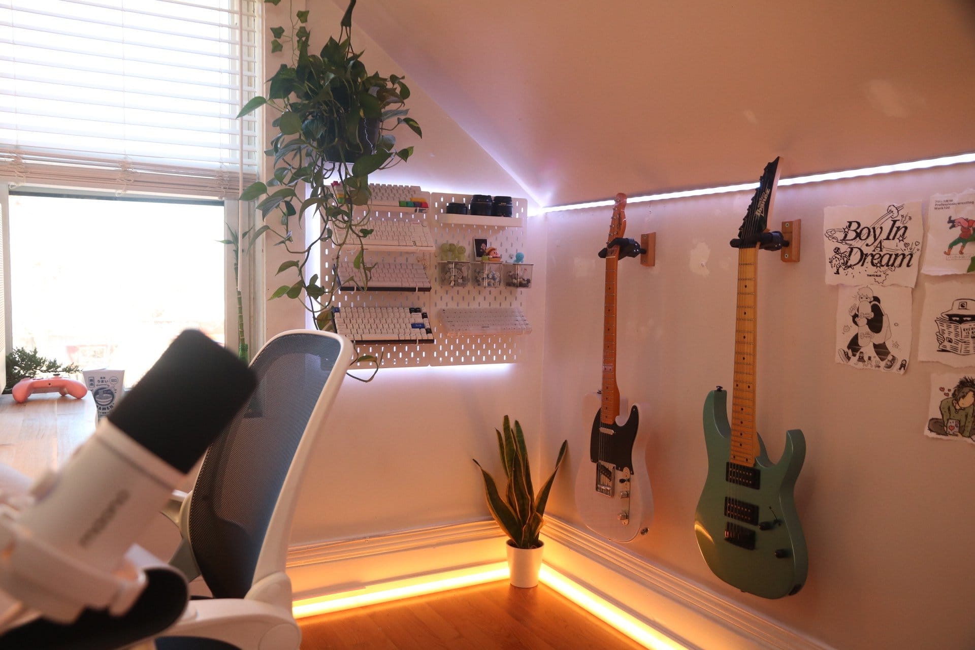 A stylish workspace with a Maono PD200X microphone, a Kerdom office chair, and two guitars displayed on the wall, complemented by abundant natural light and greenery