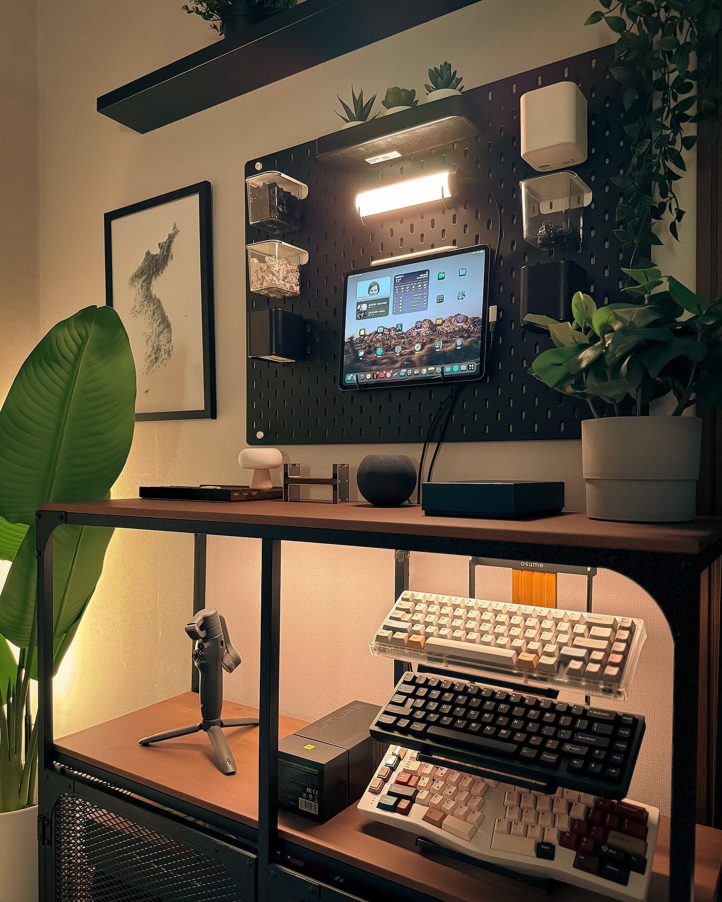A home office corner with an iPad Pro, wall-mounted pegboard, and custom mechanical keyboards