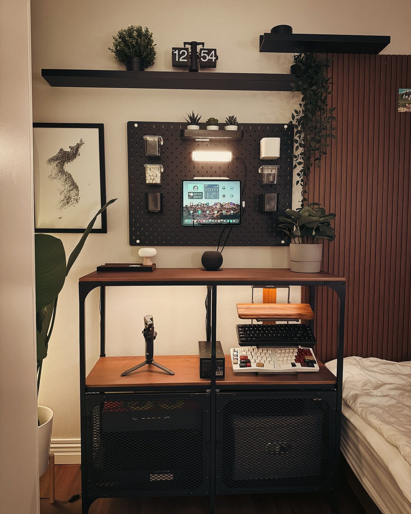 A bedroom home office corner with an iPad Pro, pegboard wall mount, and mechanical keyboards