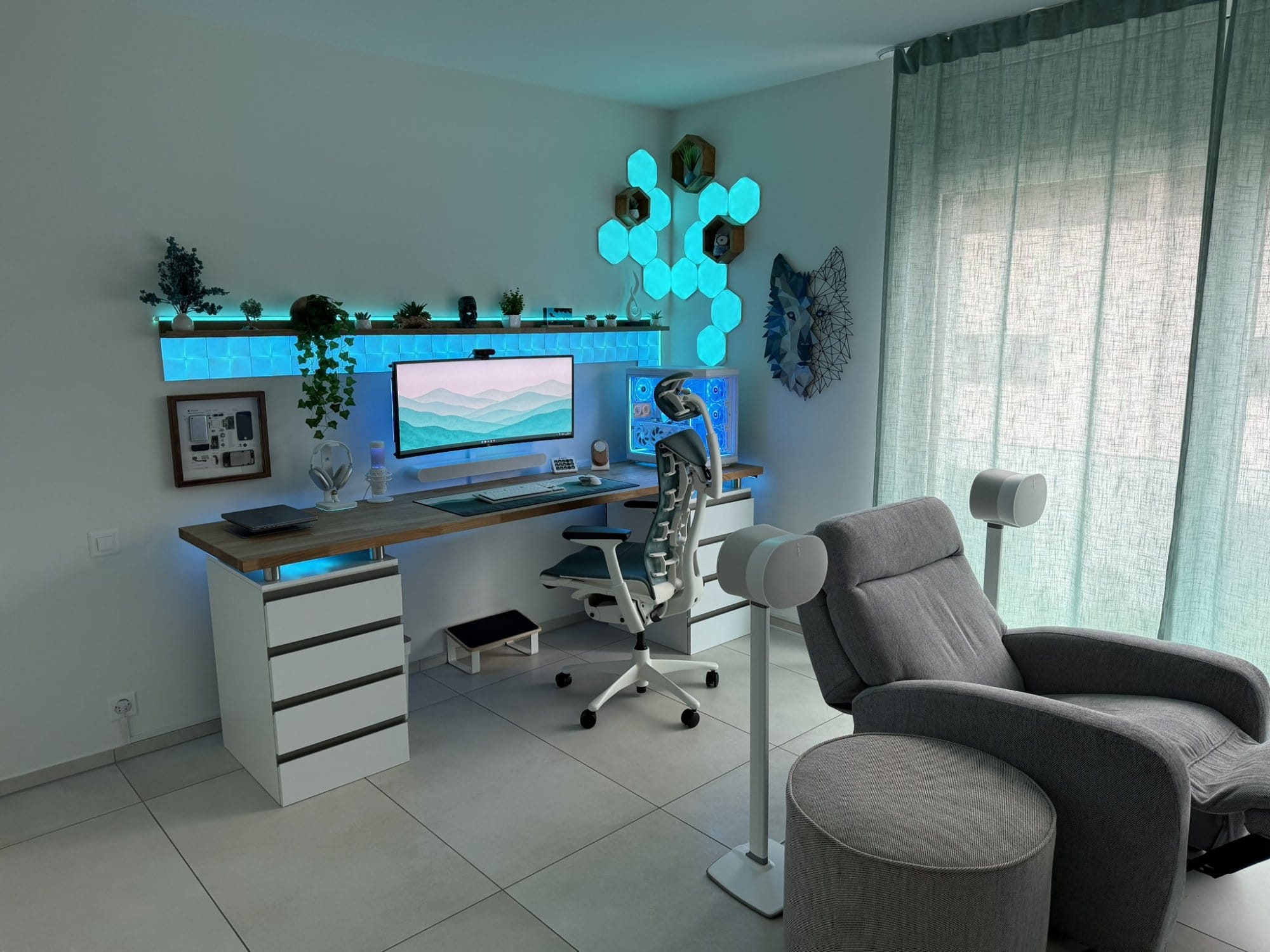 A hybrid workspace with an LG 38GN950 monitor, Herman Miller Embody chair, Nanoleaf LED panels, and a grey recliner flanked by Sonos Era 300 speakers