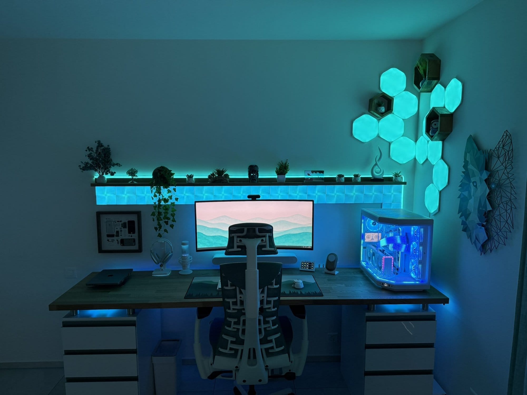 A night-time desk setup with Nanoleaf LED panels, LG 38GN950 monitor, and a Hyte Y70 PC case glowing blue