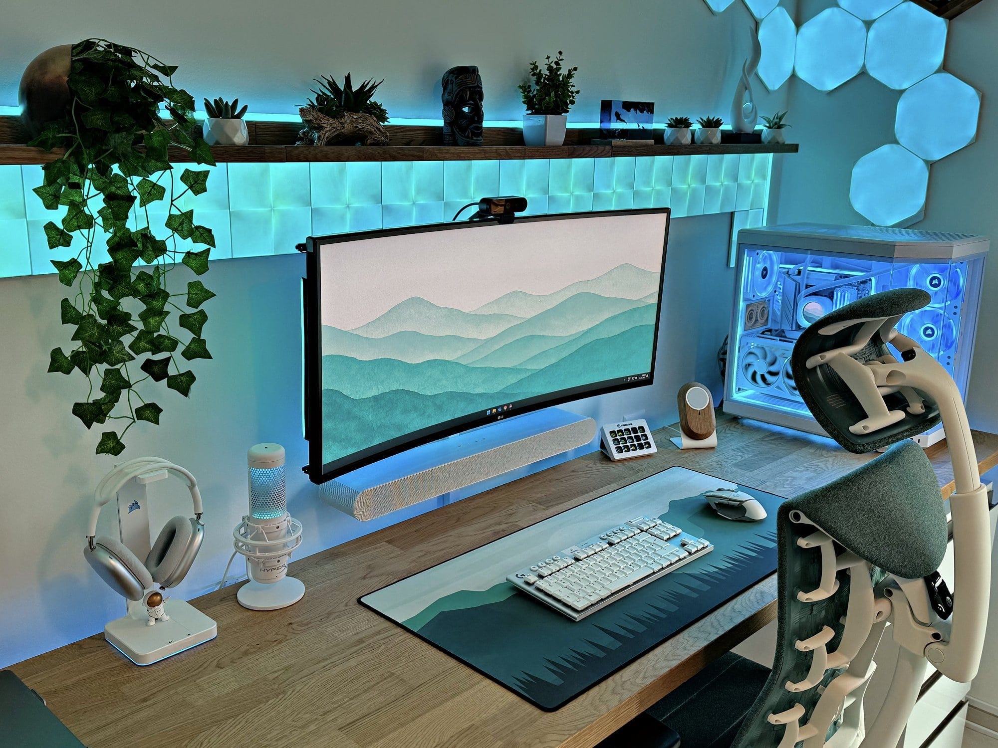 A gaming desk setup with an LG 38GN950 monitor and glowing Nanoleaf LED wall panels
