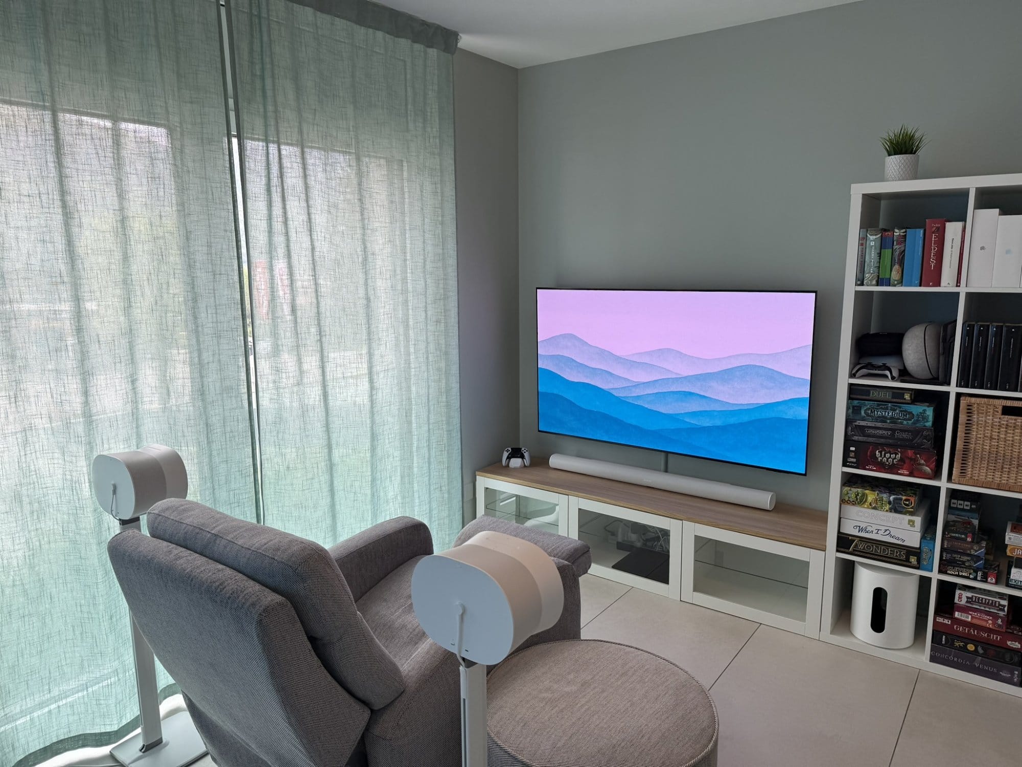 A lounge setup with a Samsung S95D OLED TV, Sonos Arc soundbar, and Sonos Sub Mini by a grey recliner