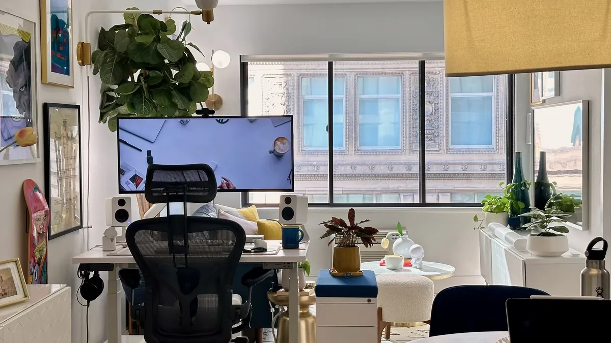 A small and bright WFH workspace with an under-desk headphone hook and lots of plants