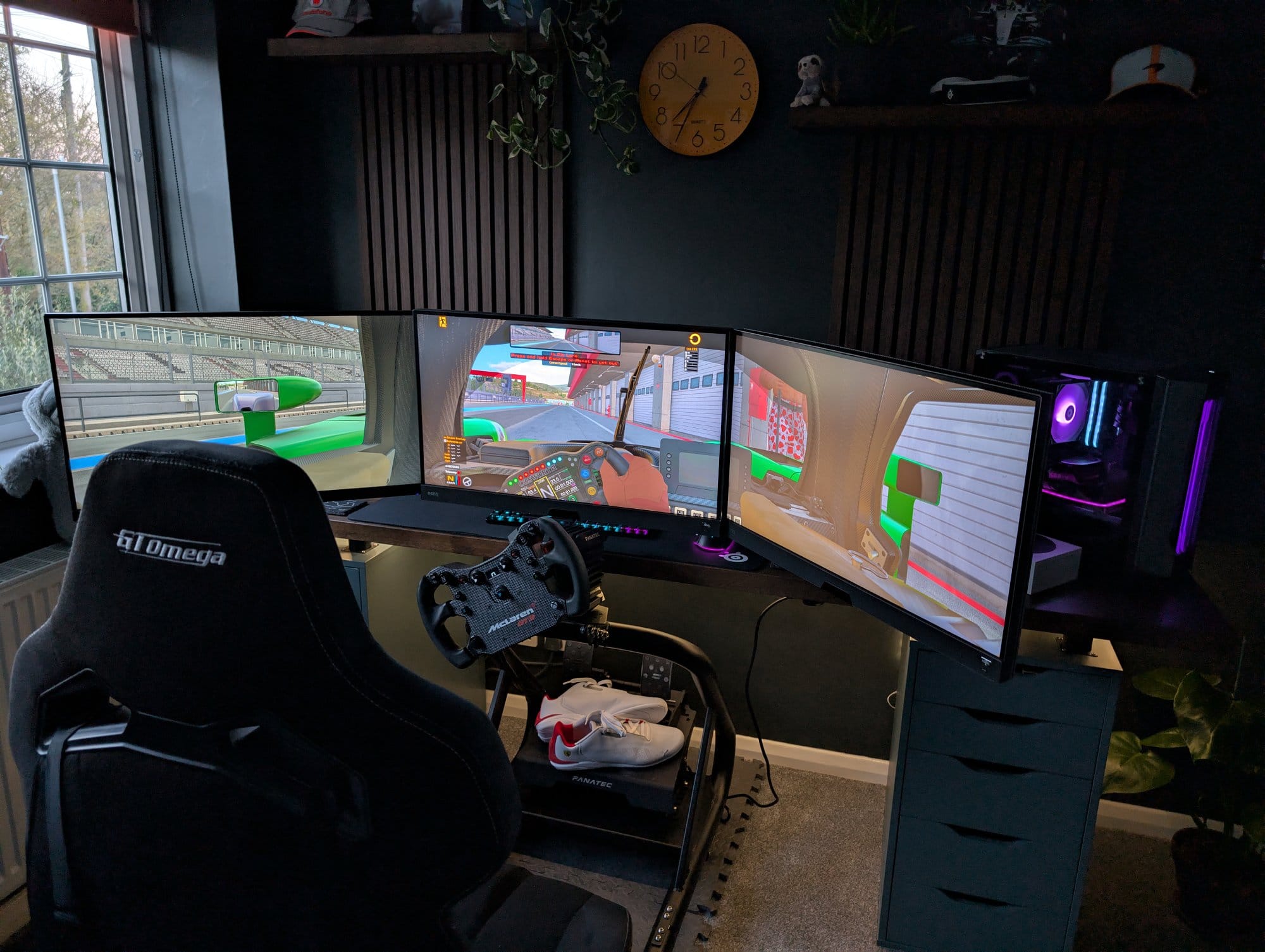 A sim racing setup with GT Omega seat, Fanatec CSL Elite McLaren GT3 wheel, and triple-monitor display