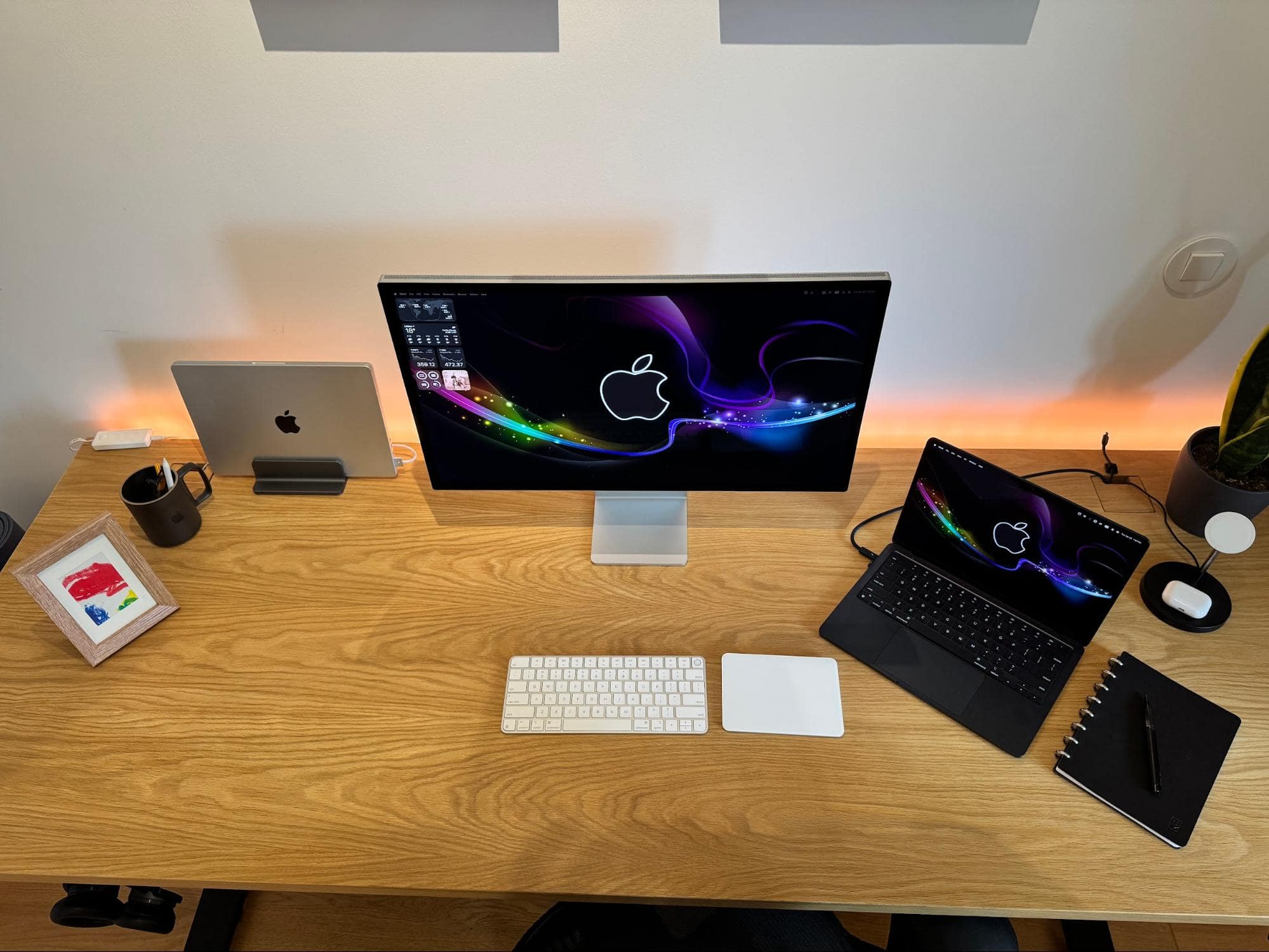 A clean desk setup with an Apple Studio Display, a MacBook Air M4, and an Apple Magic Trackpad