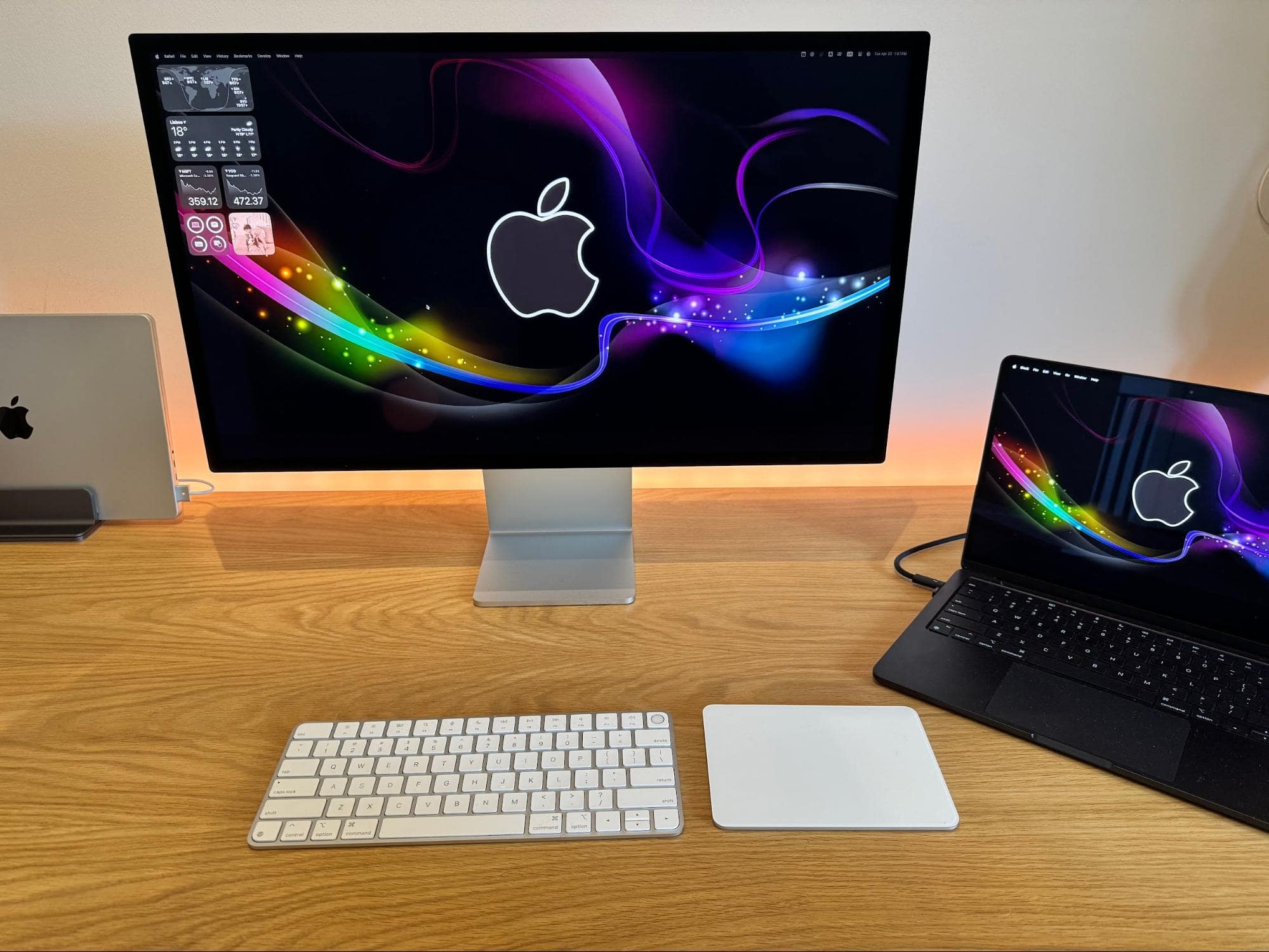 A decluttered home workspace with an Apple Studio Display, a MacBook Air M4, and an Apple Magic keyboard