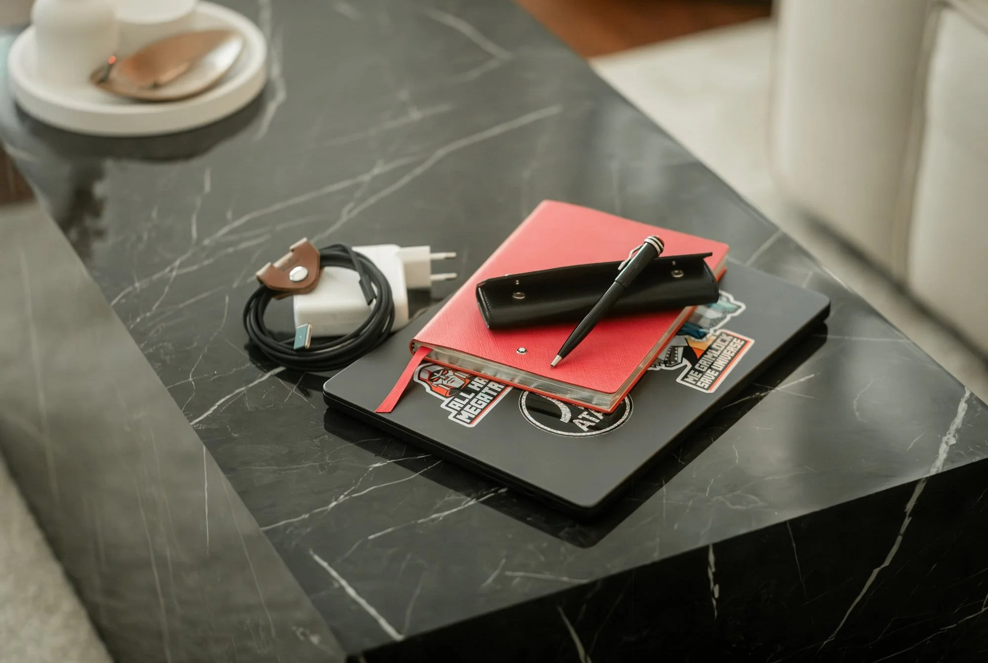 A black marble table with MacBook Pro and red Hobonichi notebook